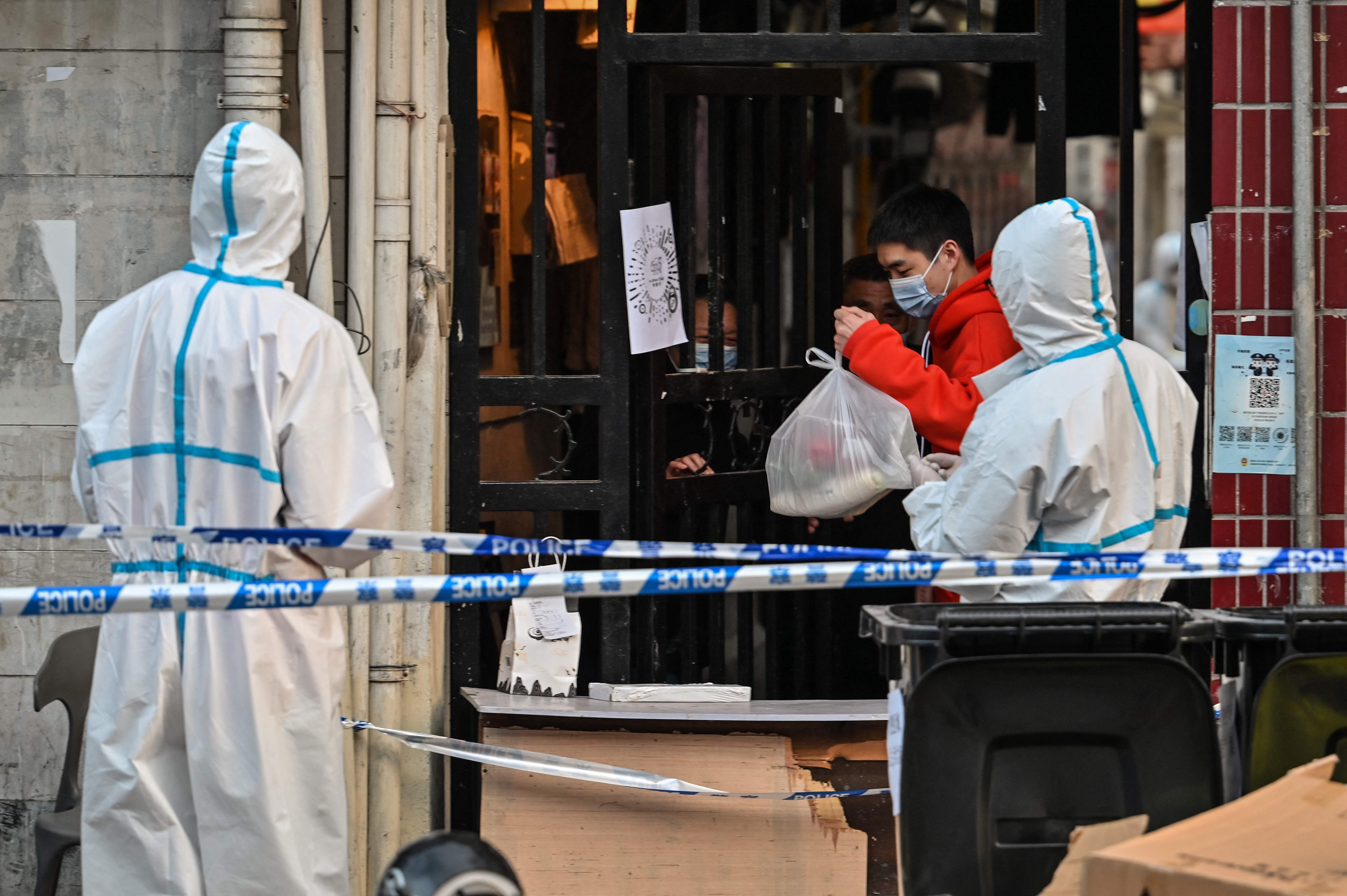 Warga yang sedang mengalami lockdown mengambil barang pesanannya yang diantar kurir