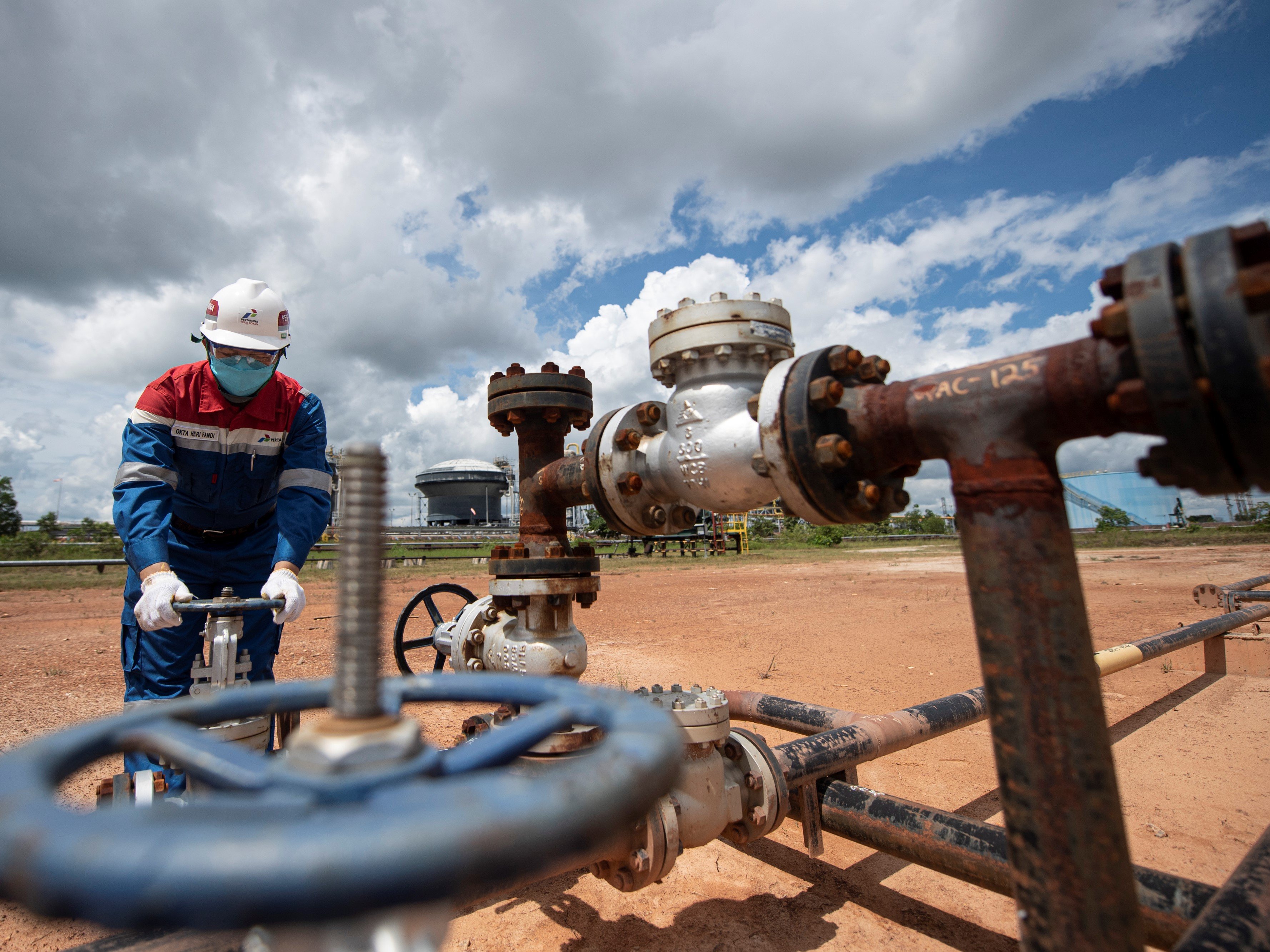 Pekerja PT Pertamina Hulu Rokan (PHR) mengontrol kerangan pipa produksi yang berasal dari sumur menuju stasiun pengumpul minyak mentah.