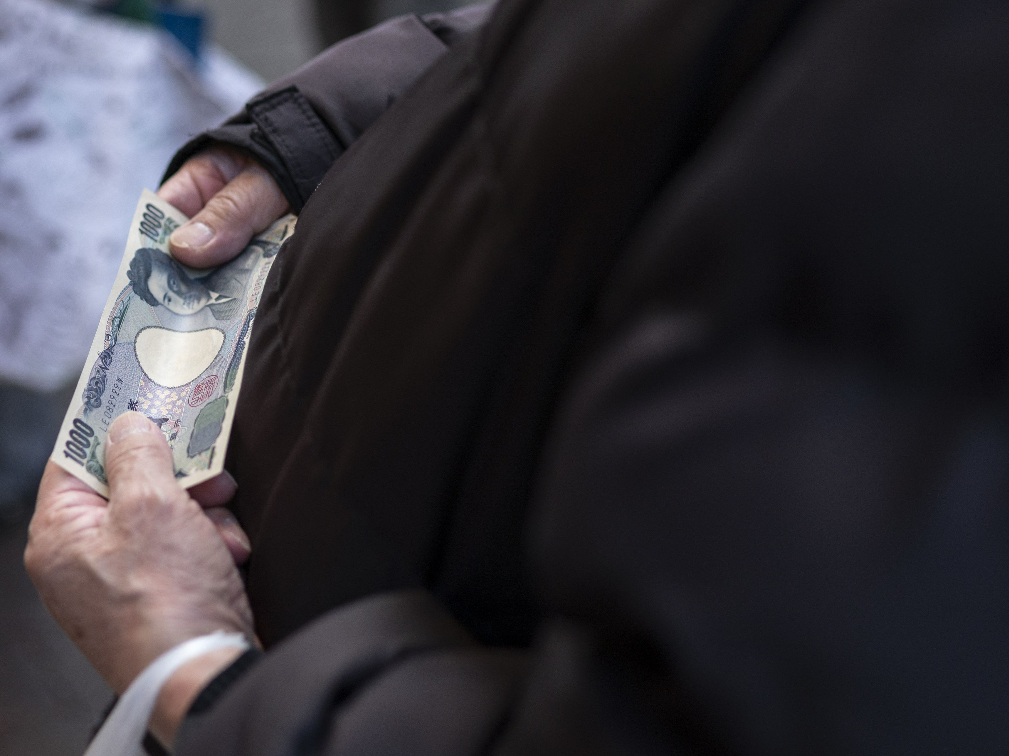 Seorang pria memegang uang 1.000 yen saat berbelanja di daerah Sunamachi Tokyo pada 9 Maret 2022. 