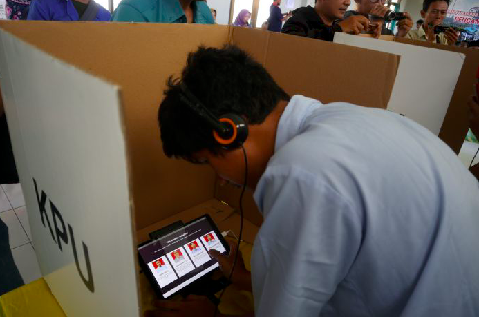 Seorang pengguna aplikasi e-voting pada smartphone android yang terhubung dengan headseat. Inovasi ini ditawarkan oleh KPU Kab Temanggung.  