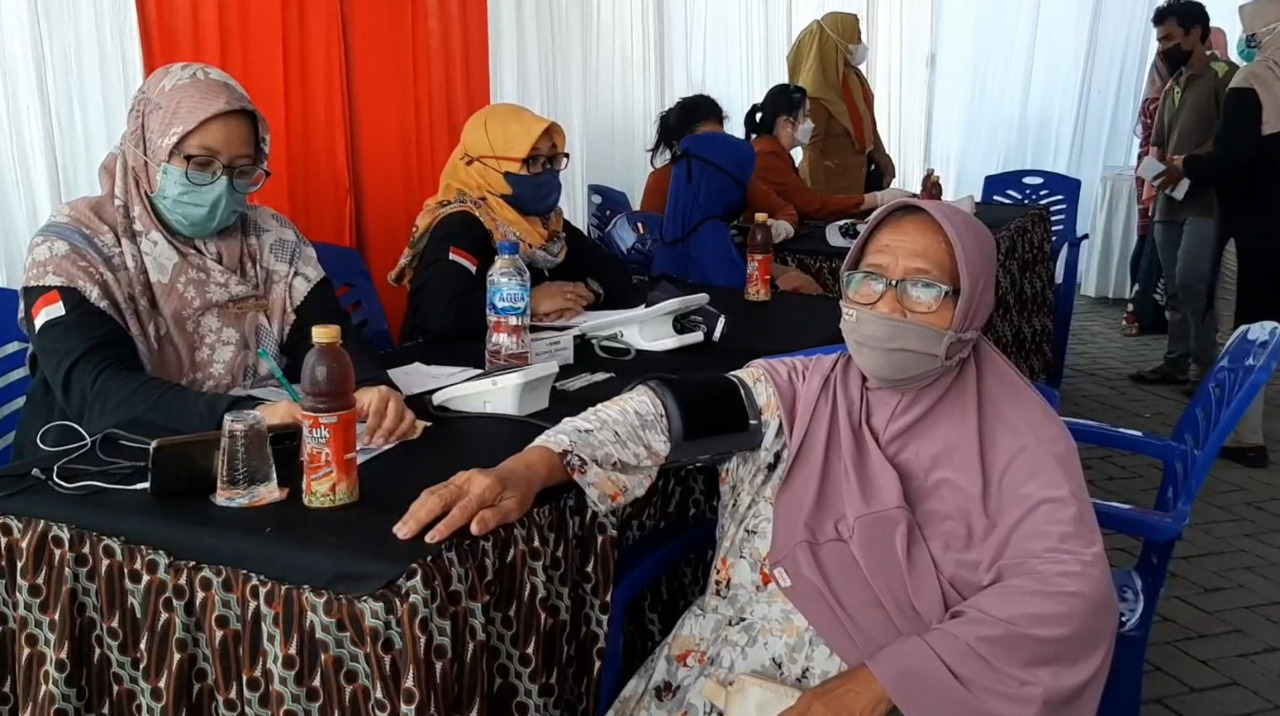 RATUSAN warga mendatangi lokasi vaksinasi booster covid-19 di Balai Desa Yosowilangun, Manyar, Gresik, Jawa Timur.