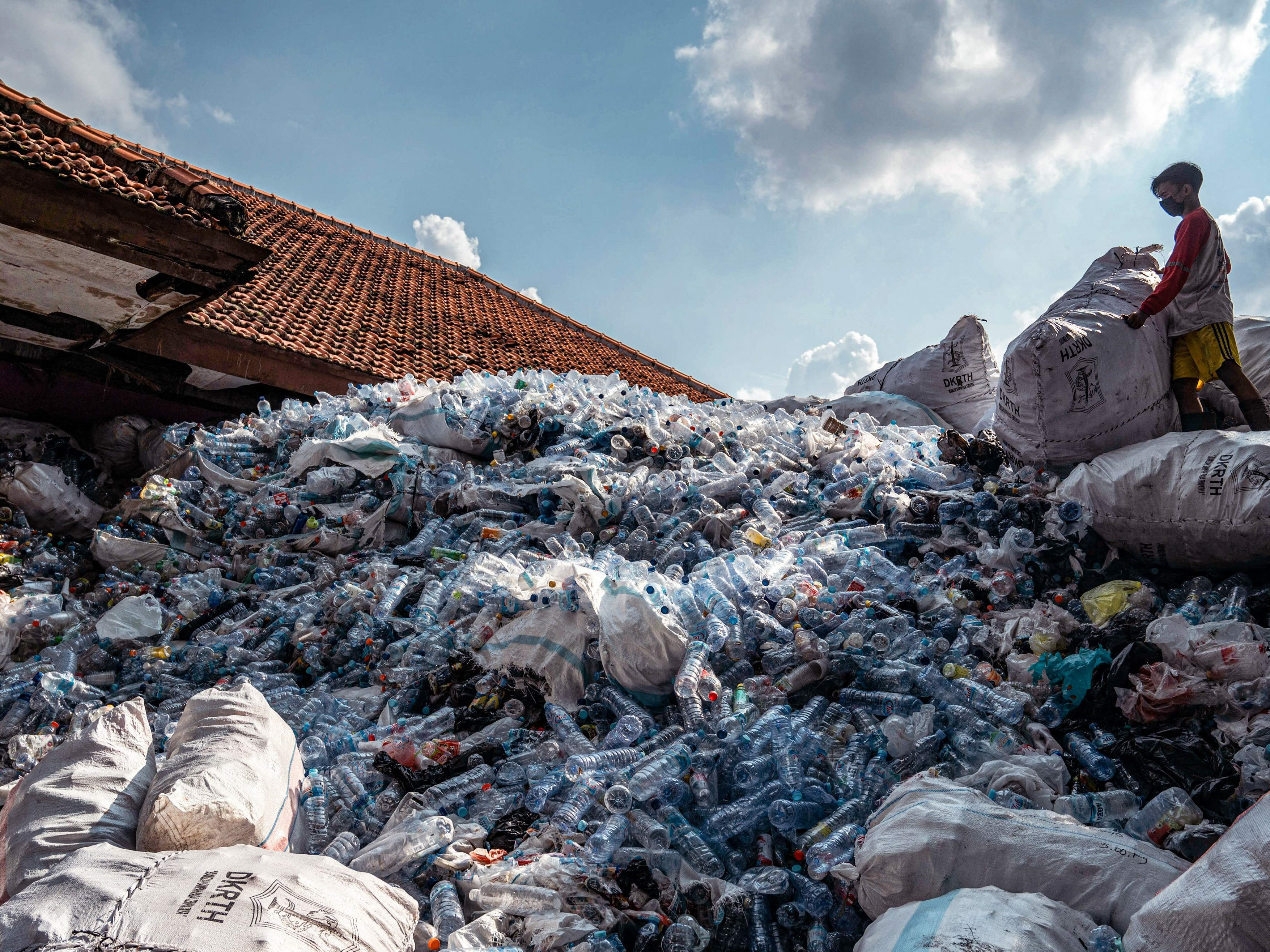 Seorang pekerja memilah dan mengemas botol plastik bekas dan tutup botol untuk ditukarkan dengan tiket bus kota di Surabaya, Jatim.