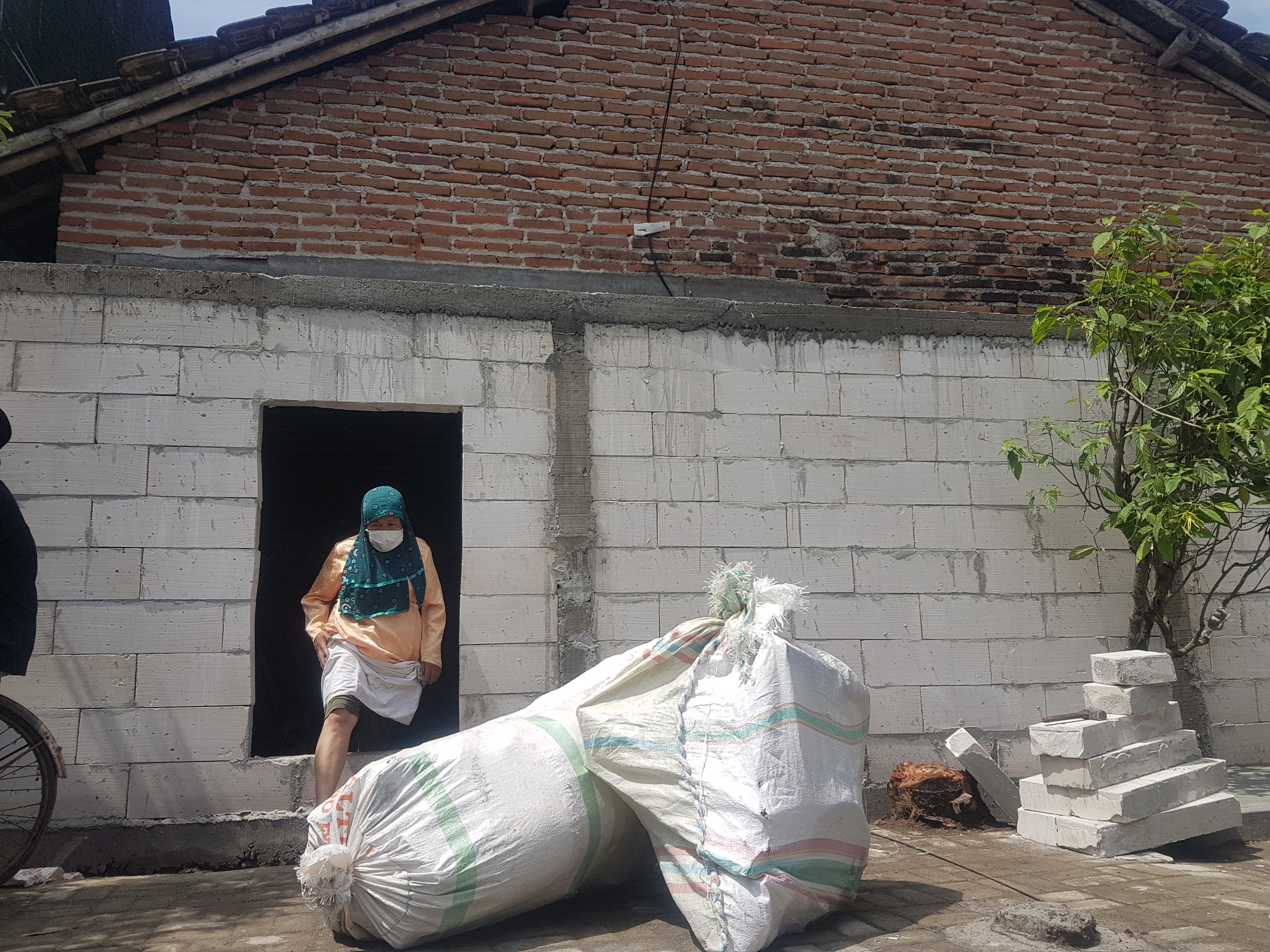 Sutikah pemilik rumah yang tertutup tembok mengosongkan rumahnya di Desa Mejobo, Kecamatan Mejobo, Kabupaten Kudus, Selasa (8/3/2022). 