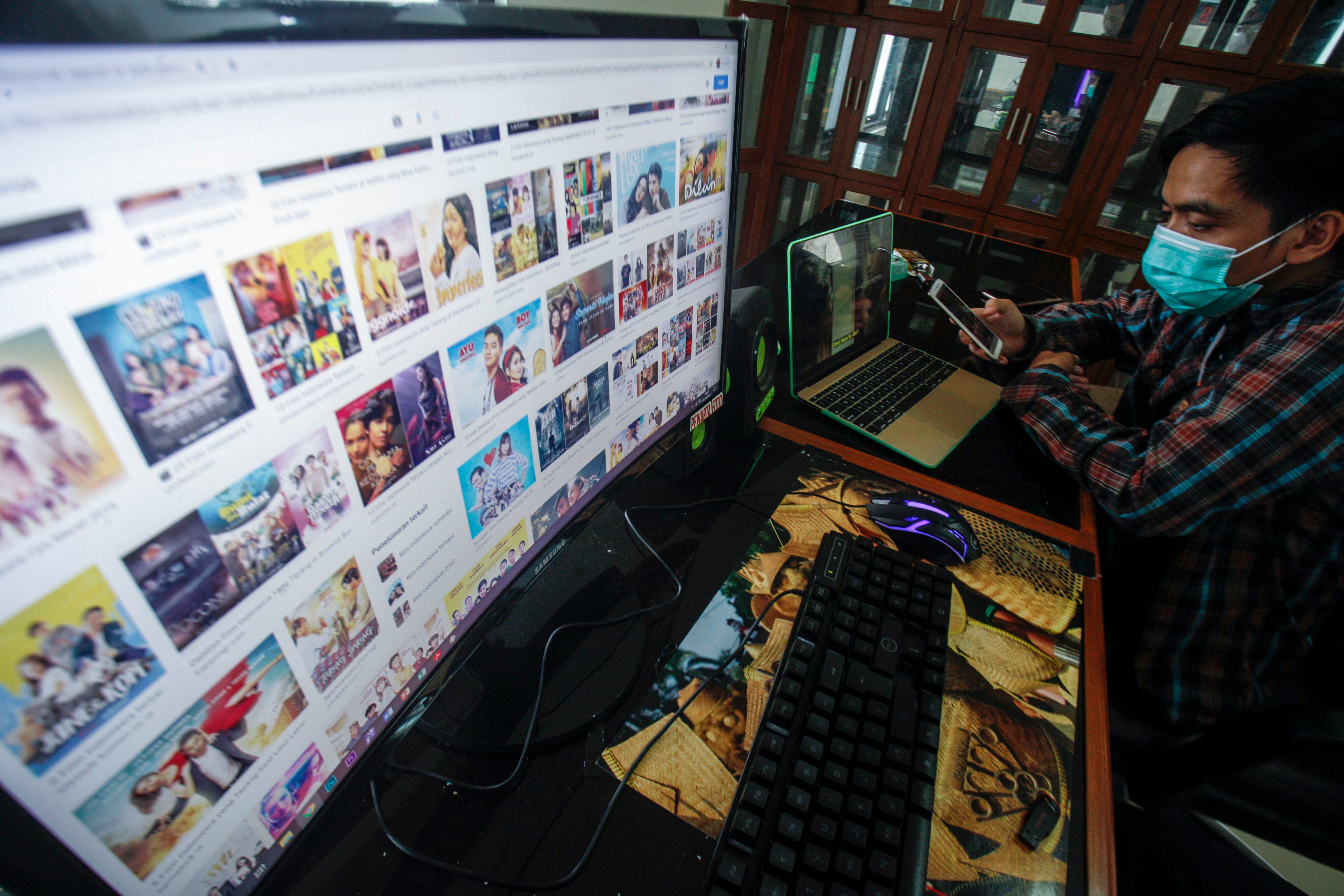 Warga mengakses layanan film daring melalui perangkat elektronik di Cibinong, Bogor, Jawa Barat.