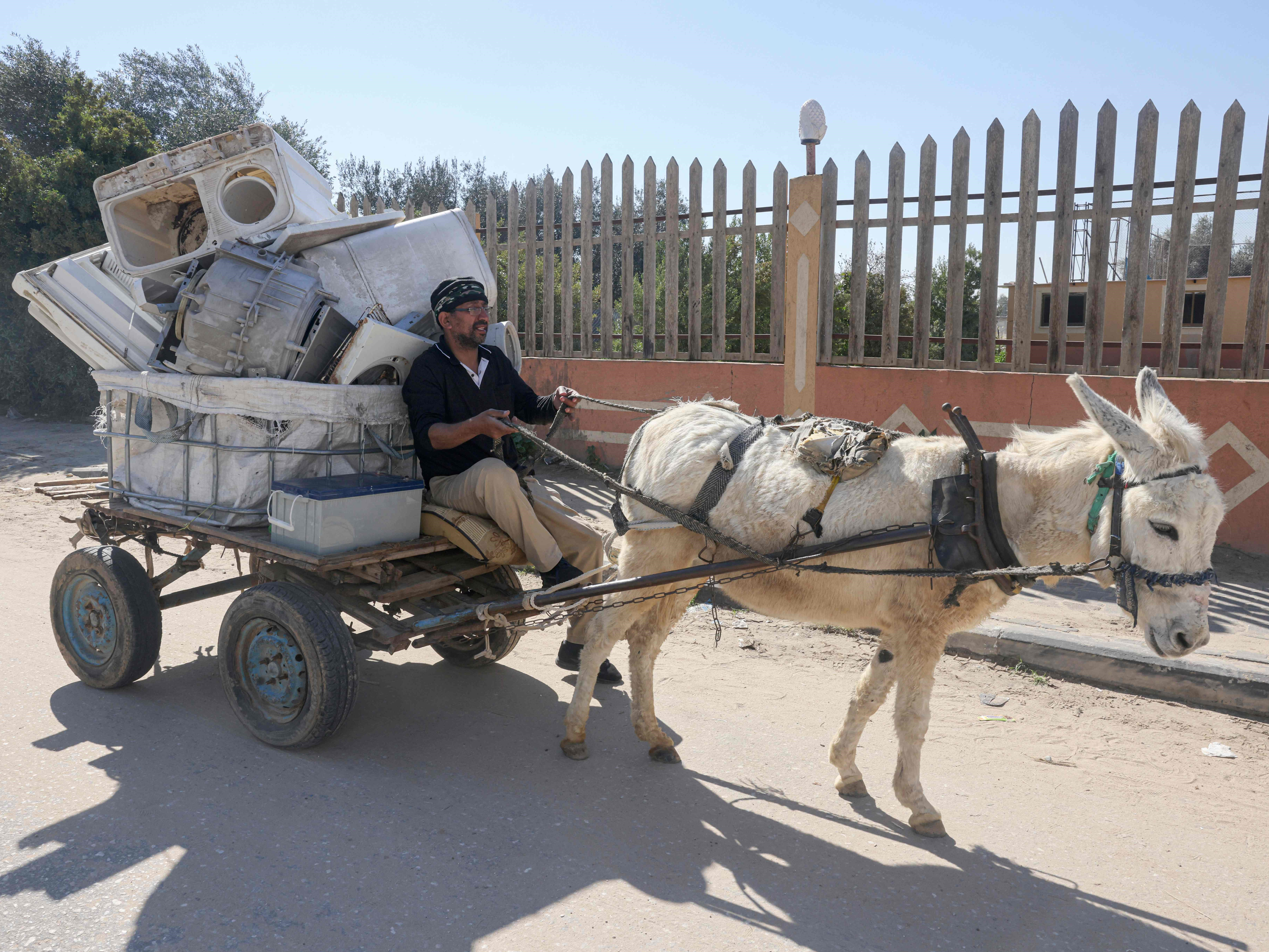 Seorang pria Palestina mengumpulkan baterai bekas ke gerobak keledai untuk dijual kembali untuk didaur ulang di Khan Yunis, Jalur Gaza.