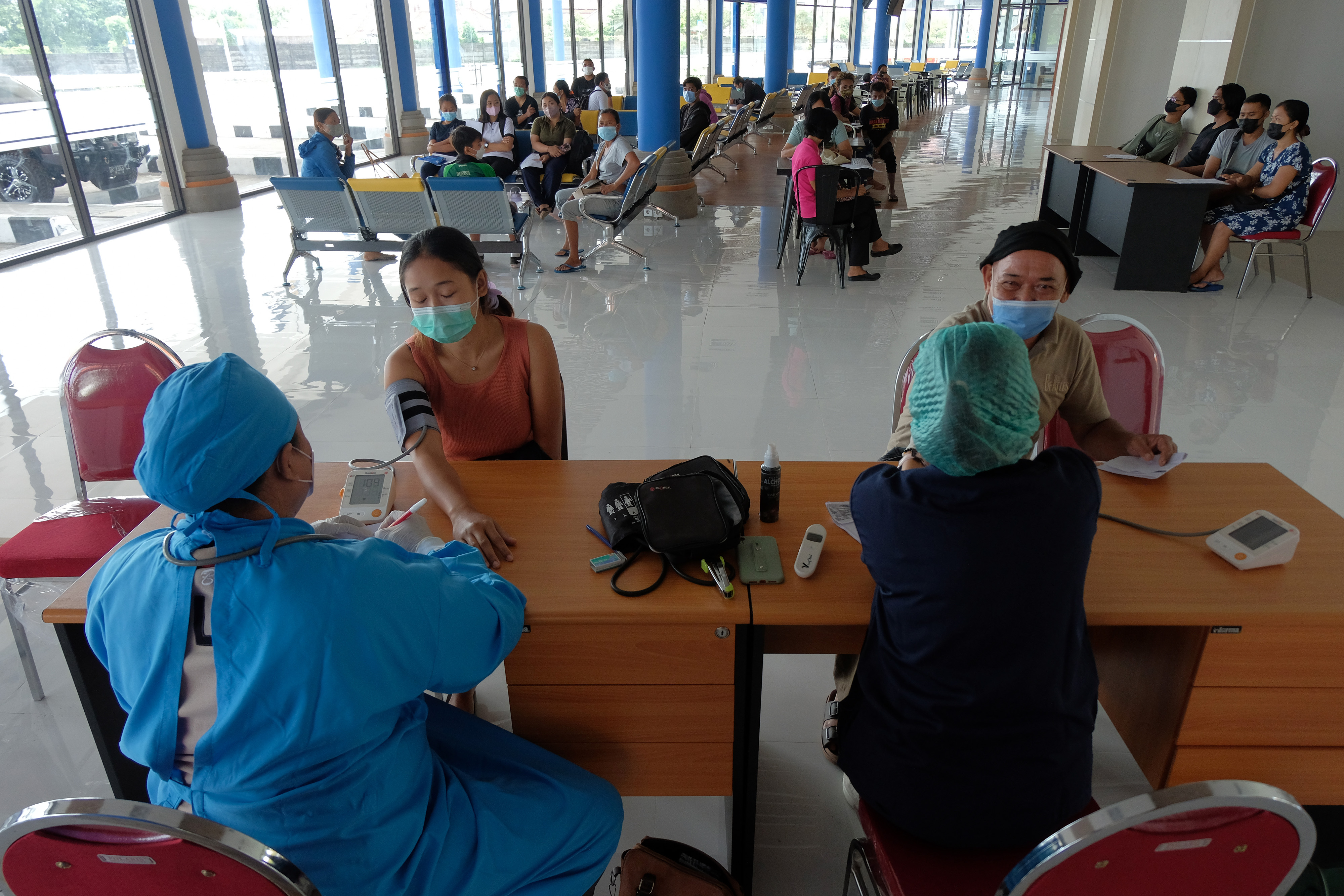  VAKSINASI DI BALI: Petugas kesehatan melakukan skrining kepada penumpang bus dan disuntikkan vaksin dosis ketiga di Terminal Mengwi, Bali.