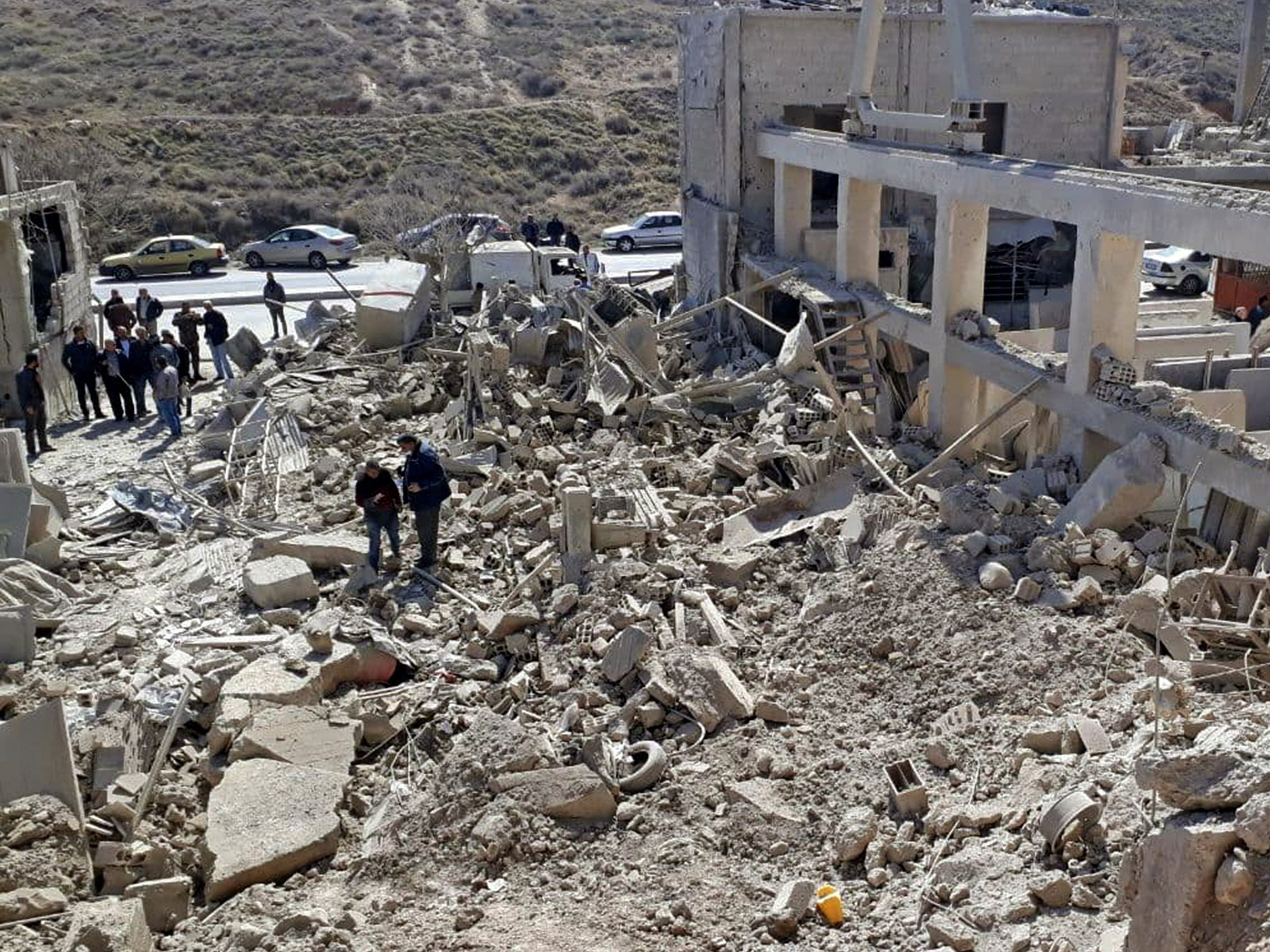 Orang-orang memeriksa bangunan yang rusak setelah serangan rudal Israel sebelum fajar di dekat ibu kota Damaskus, Senin (7/3).