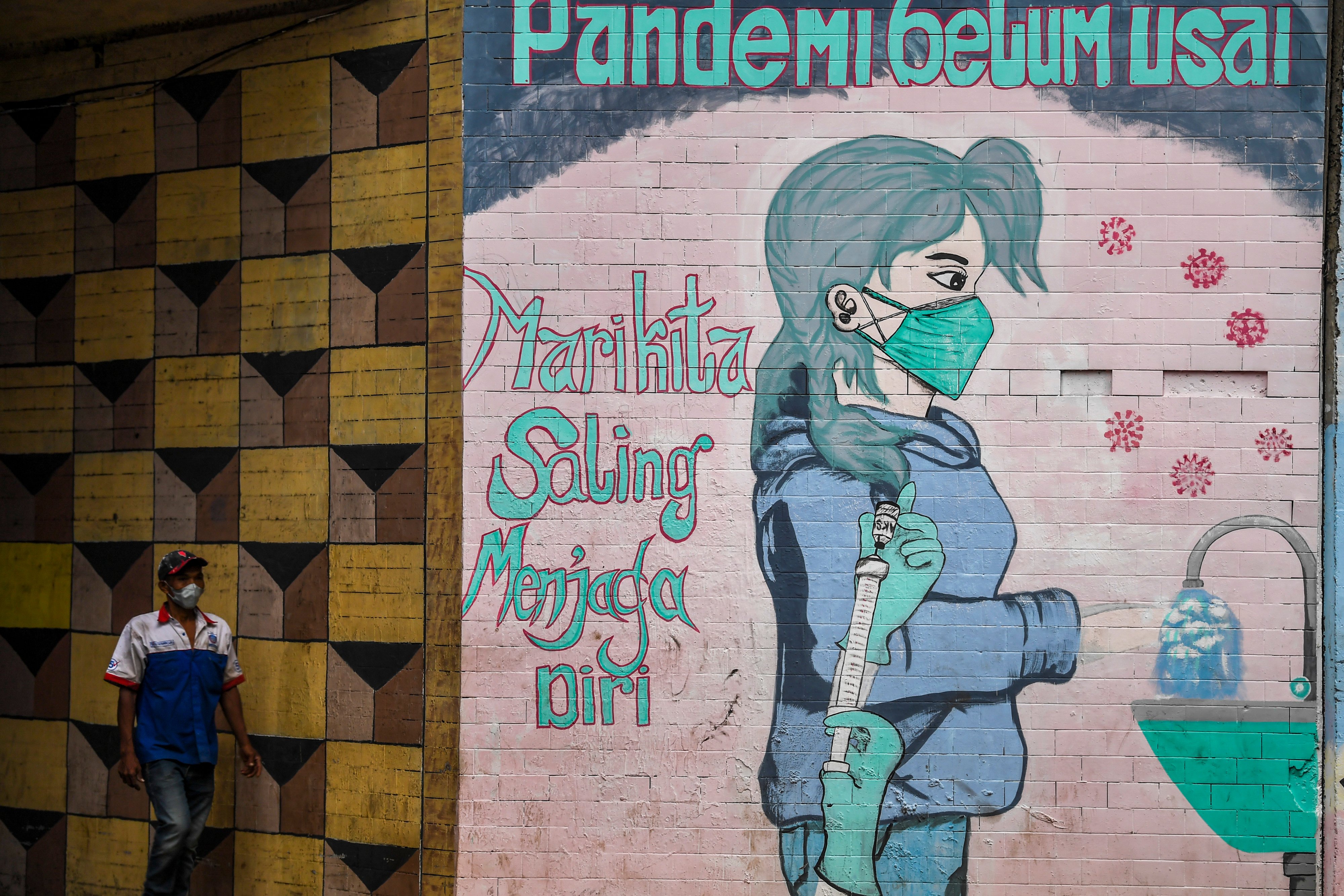 Warga berjalan di dekat mural bertema pencegahan penyebaran COVID-19 di Jakarta, Rabu (2/3/2022).