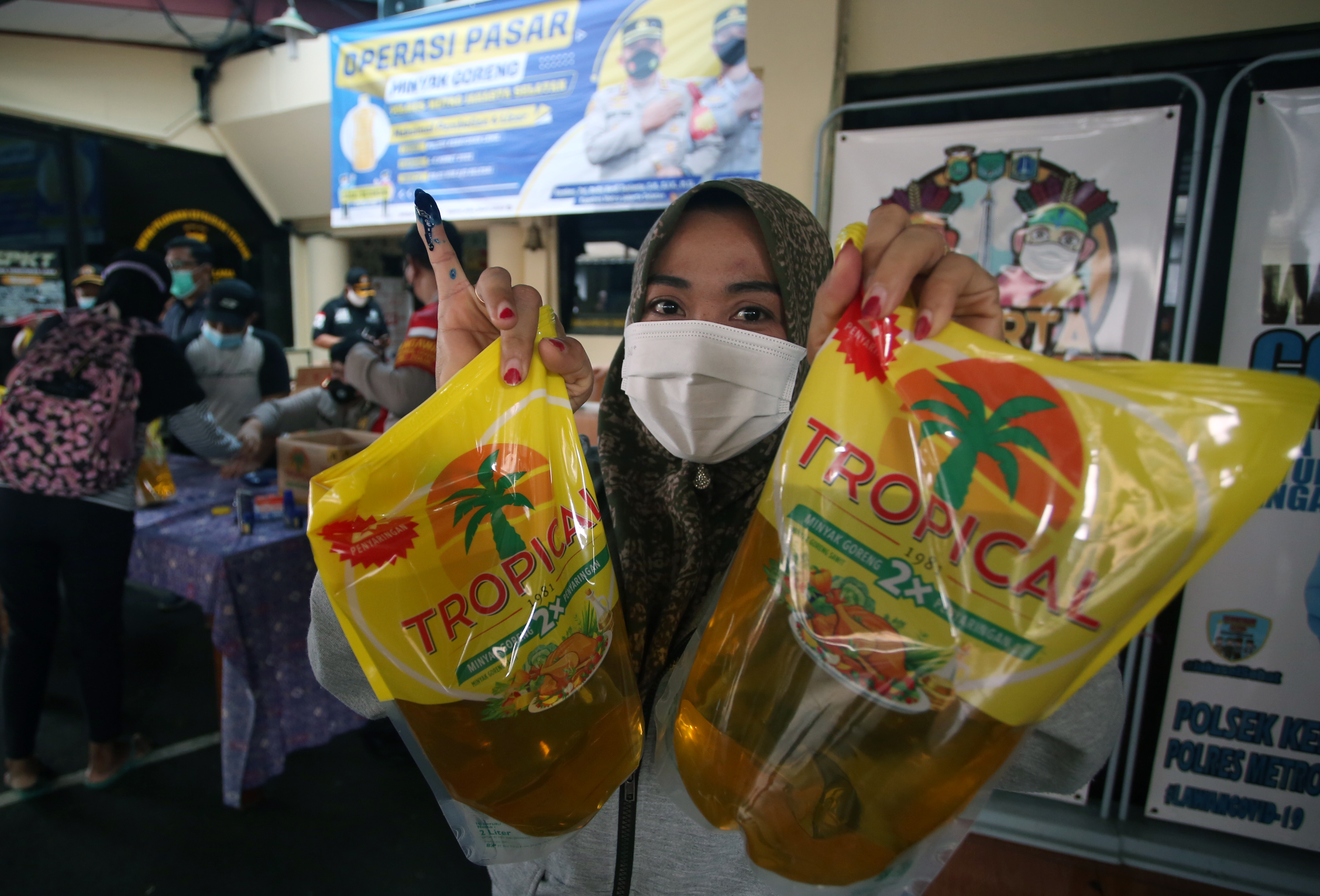 Warga menunjukan minyak goreng dan jari yang sudah diberi tinta sebagai tanda pembelian.