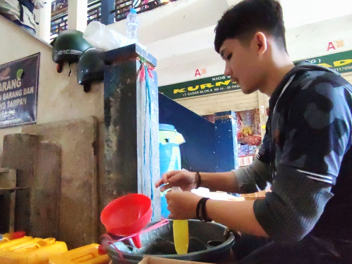 Pedagang sembako di Pasar Panorama Lembang Kabupaten Bandung Barat sedang mengemas minyak goreng curah ke dalam plastik, Rabu (23/3).