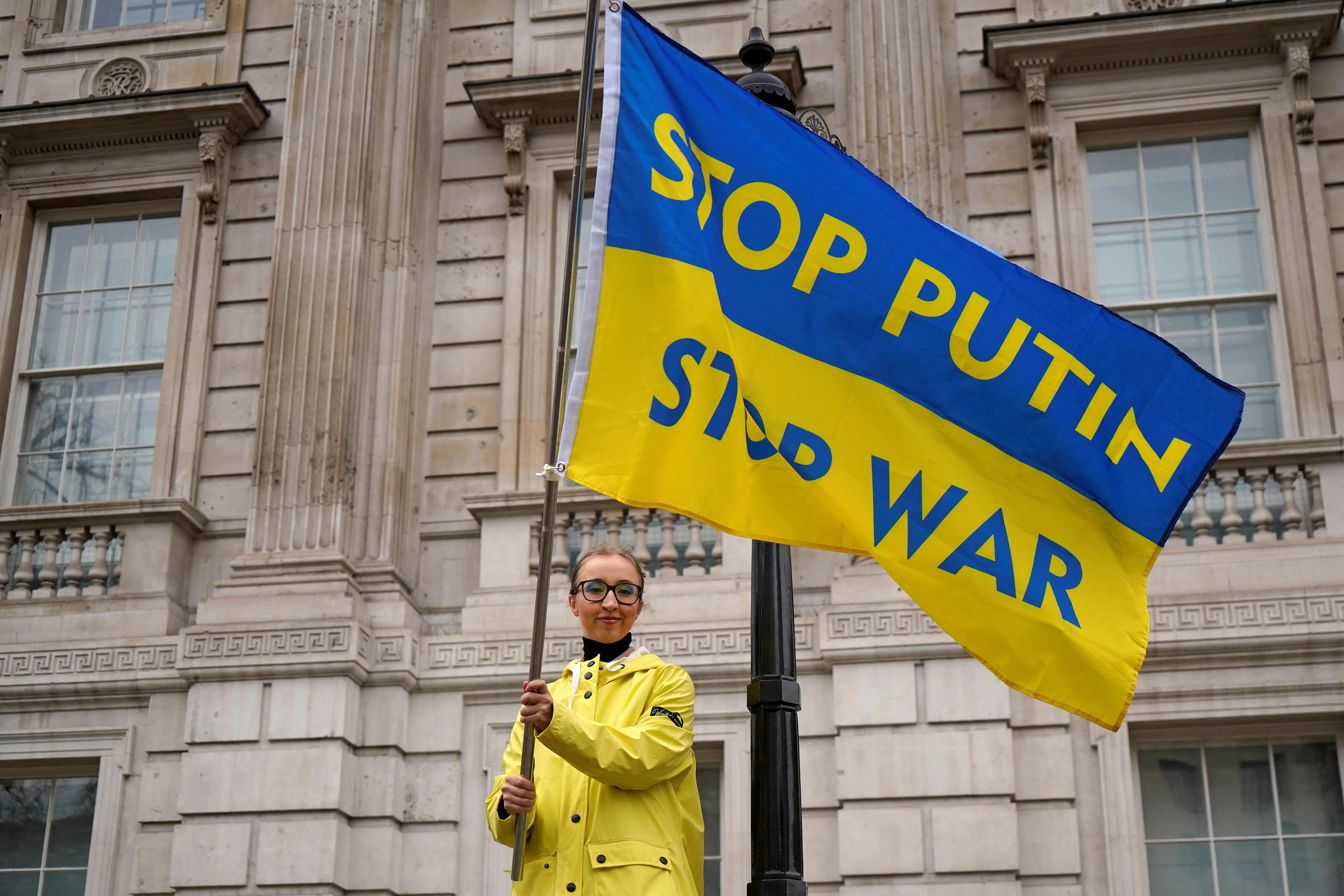 Warga di London memegang bendera bernada protes terhadap kebijakan Presiden Rusia Vladimir Putin.