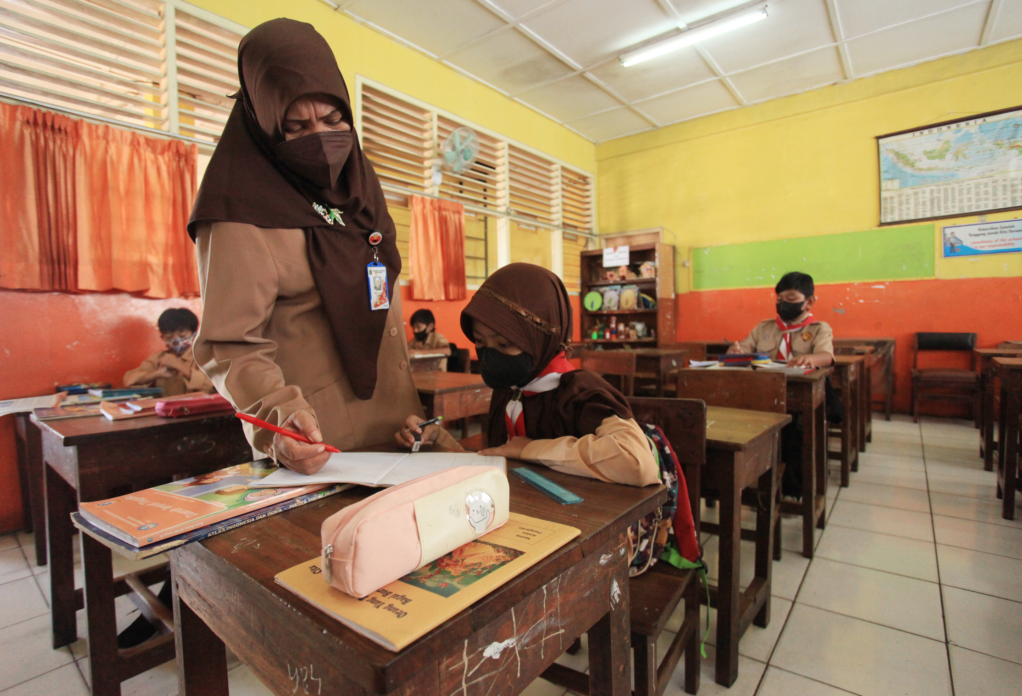 Guru memberi arahan kepada seorang siswi saat mengikuti Pembelajaran Tatap Muka (PTM) SDN Pondok Pinang 01, Jakarta , Rabu (23/3).