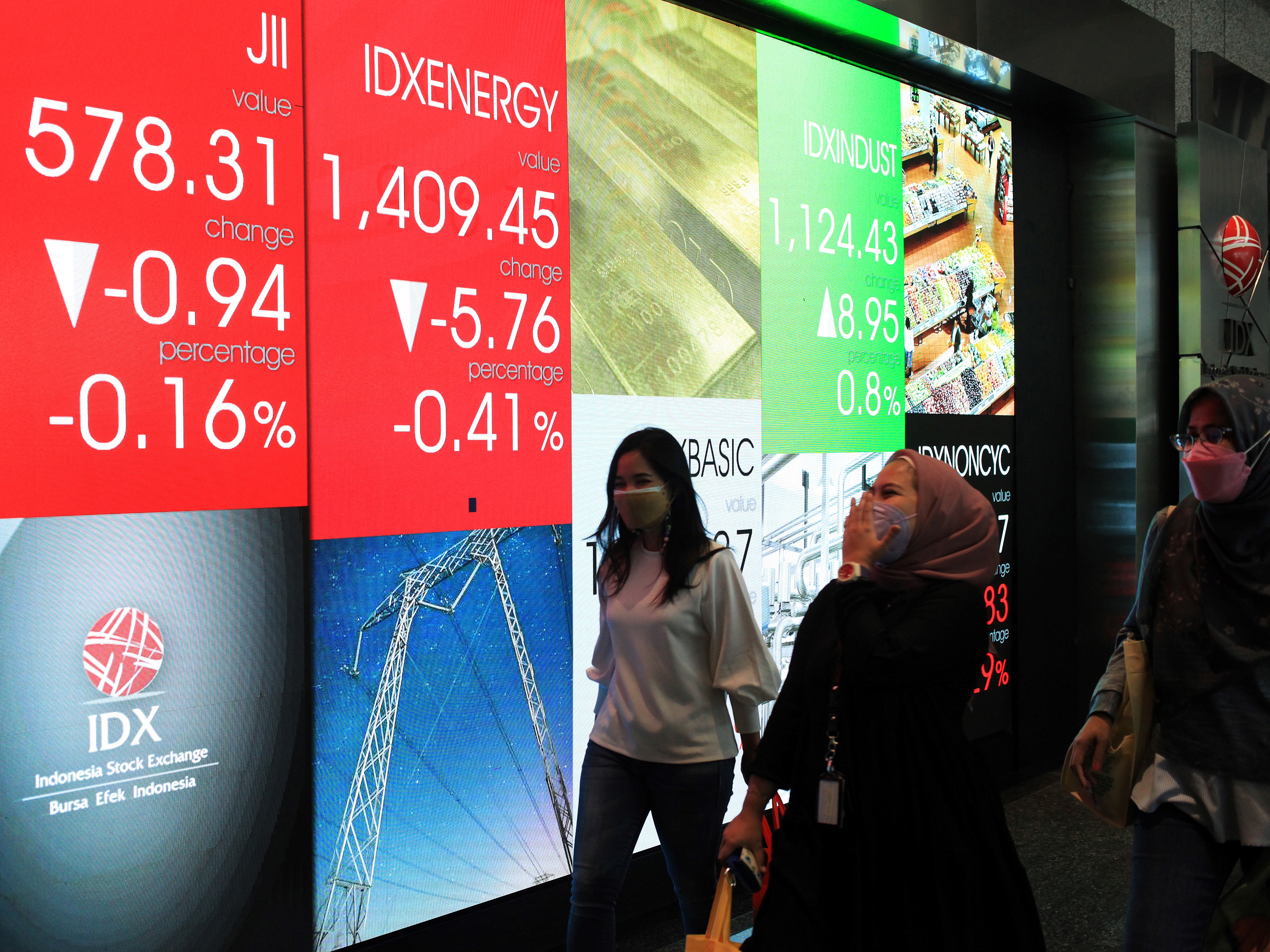 Pekerja melintas di depan layar indeks harga saham gabungan (IHSG) di Gedung Bursa Efek Indonesia, Jakarta, Jumat (11/3/2022).