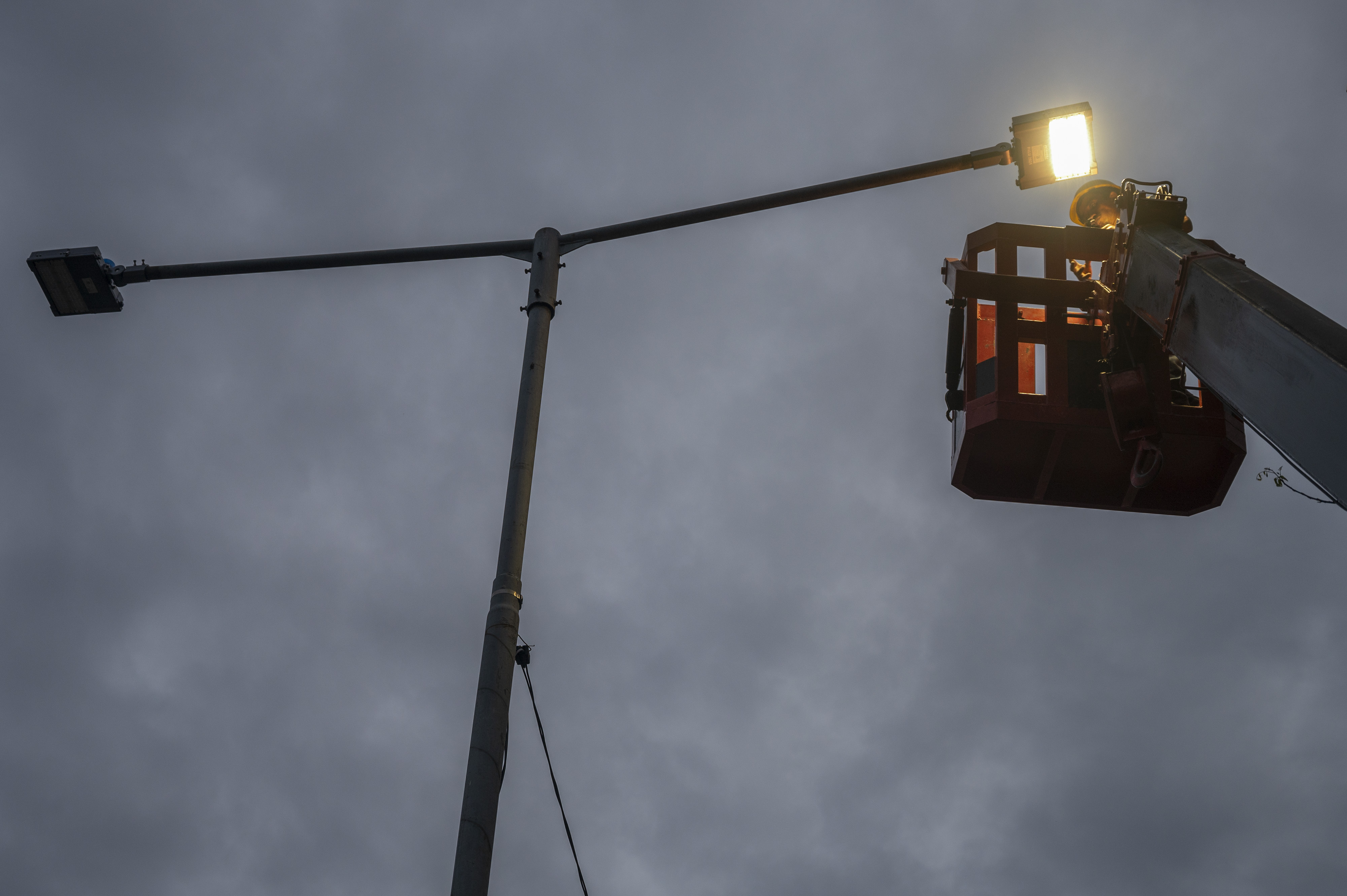 Pekerja tengah memperbaiki lampu penerangan jalan umum di Sulawesi Tengah