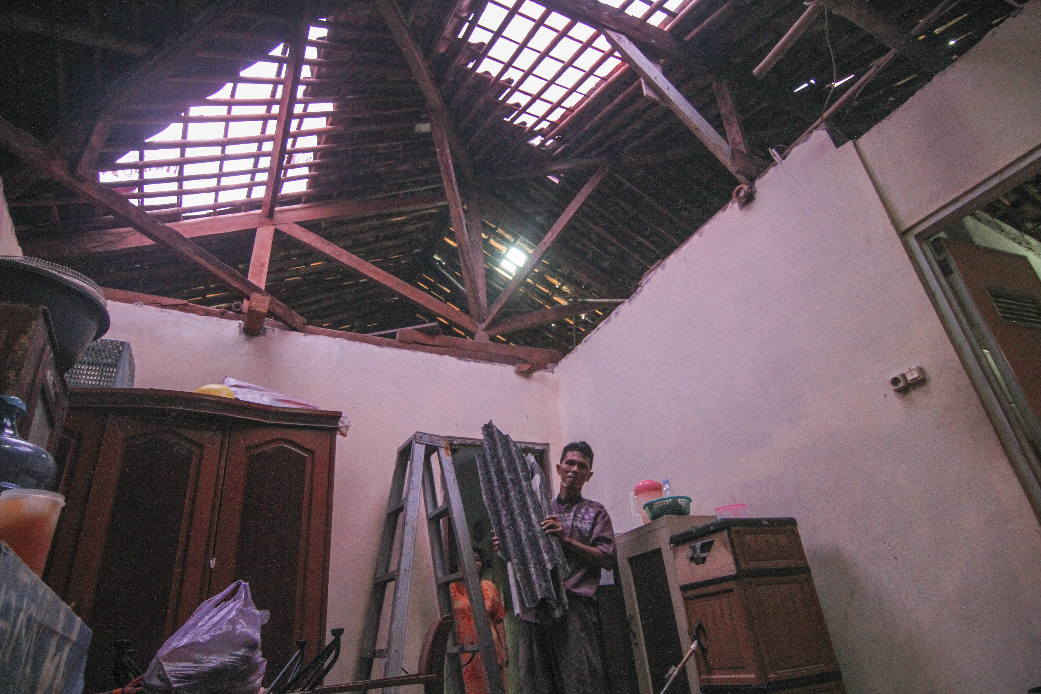  Warga membersihkan serpihan atap bangunan rumahnya akibat angin puting beliung di Bojongsari, Depok, Jawa Barat