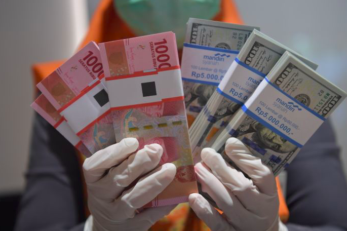 Pegawai bank menunjukan uang rupiah dan dolar AS.