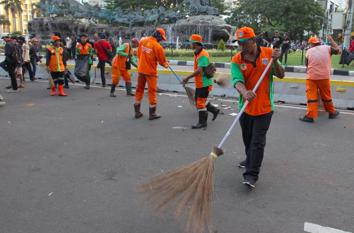 etugas dari Suku Dinas Lingkungan Hidup Kota Administrasi Jakarta Pusat membersihkan sampah seusai aksi massa buruh