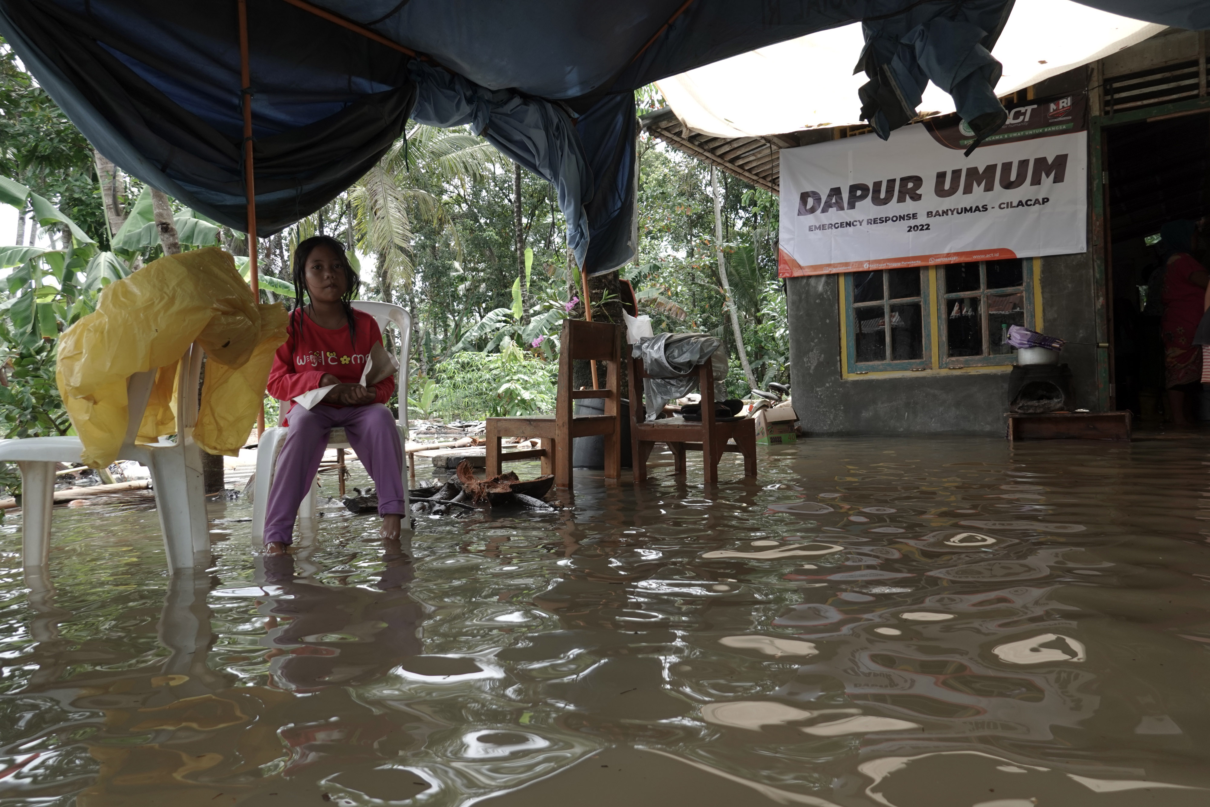 Seorang anak memakan nasi bungkus dari dapur umum yang terendam banjir di Desa Nusadadi, Sumpuh, Banyumas, Jateng, Jumat (18/3)