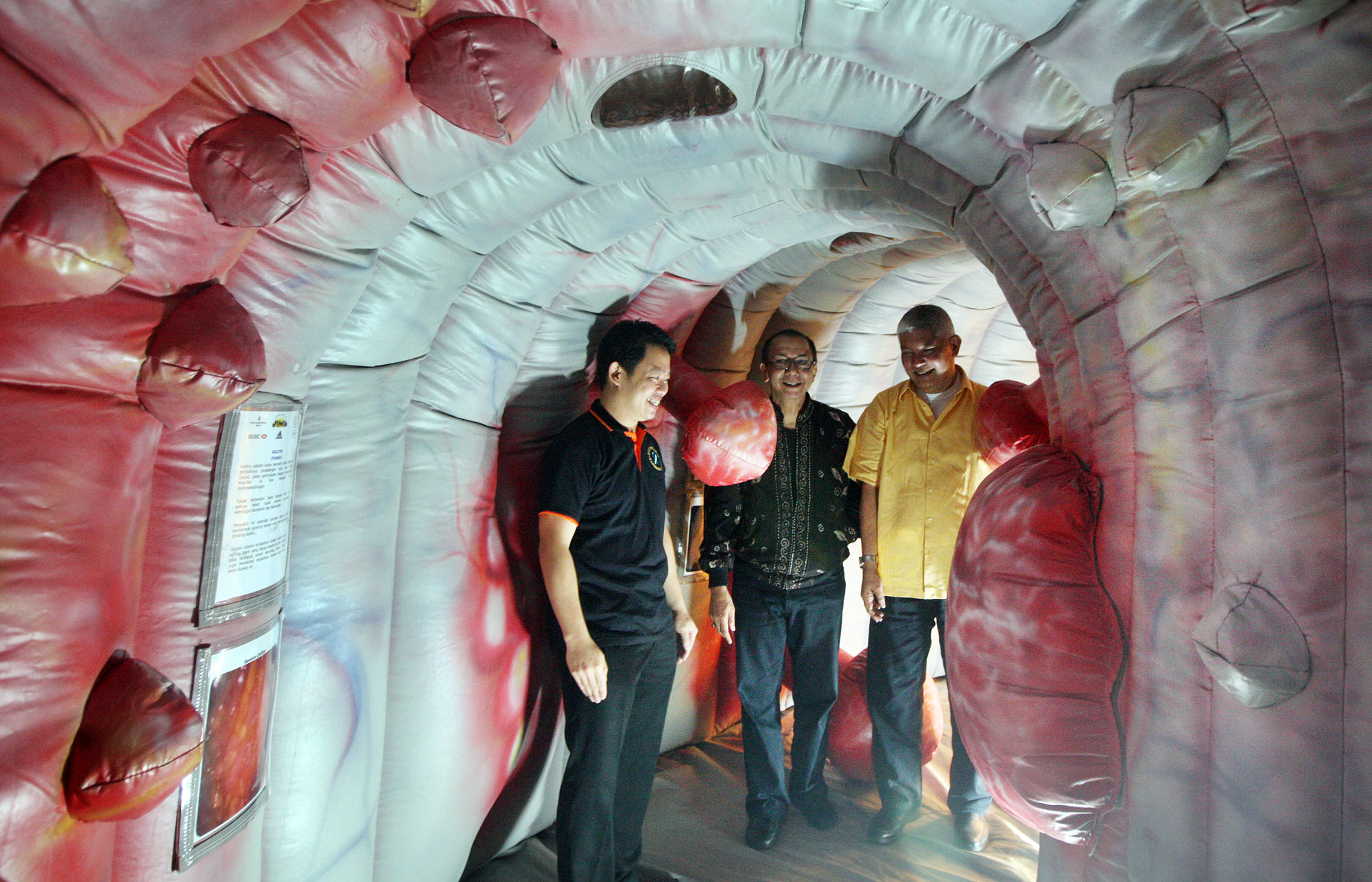 Tiga pasien kanker usus besar memasuki replika usus saat acara temu pasien kanker usus besar di Hotel Sahid, Jakarta Selatan.