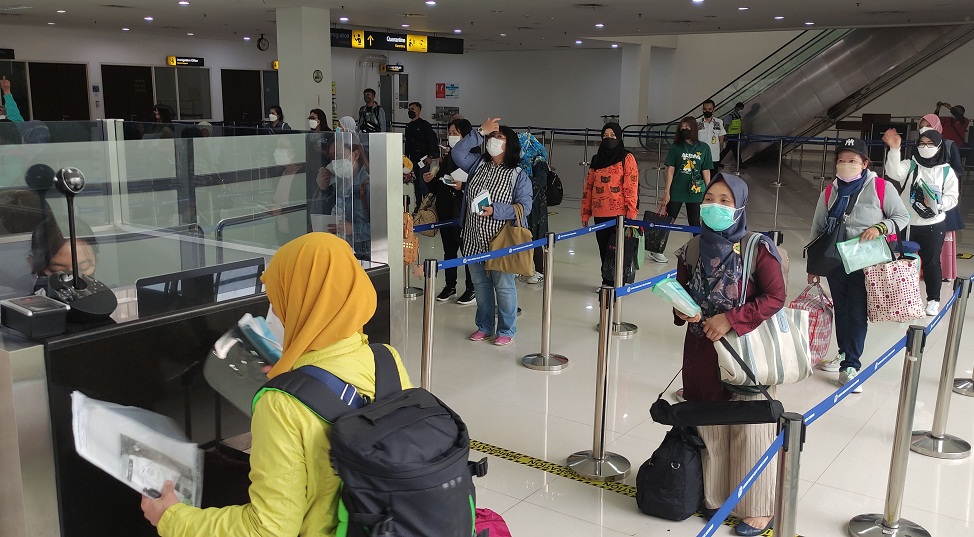 Para PMI yang baru tiba dari luar negari antri sebelum keluar dari Bandara Juanda, Sidoarjo, Jatim.