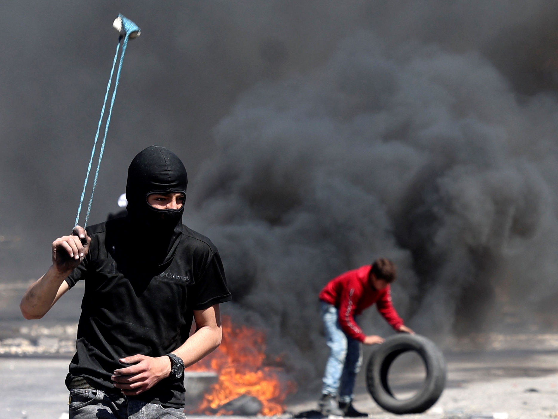 Pengunjuk rasa Palestina menggunakan ketapel untuk melemparkan batu ke keamanan Israel di tengah bentrokan selama demonstrasi, Jumat (15/4).