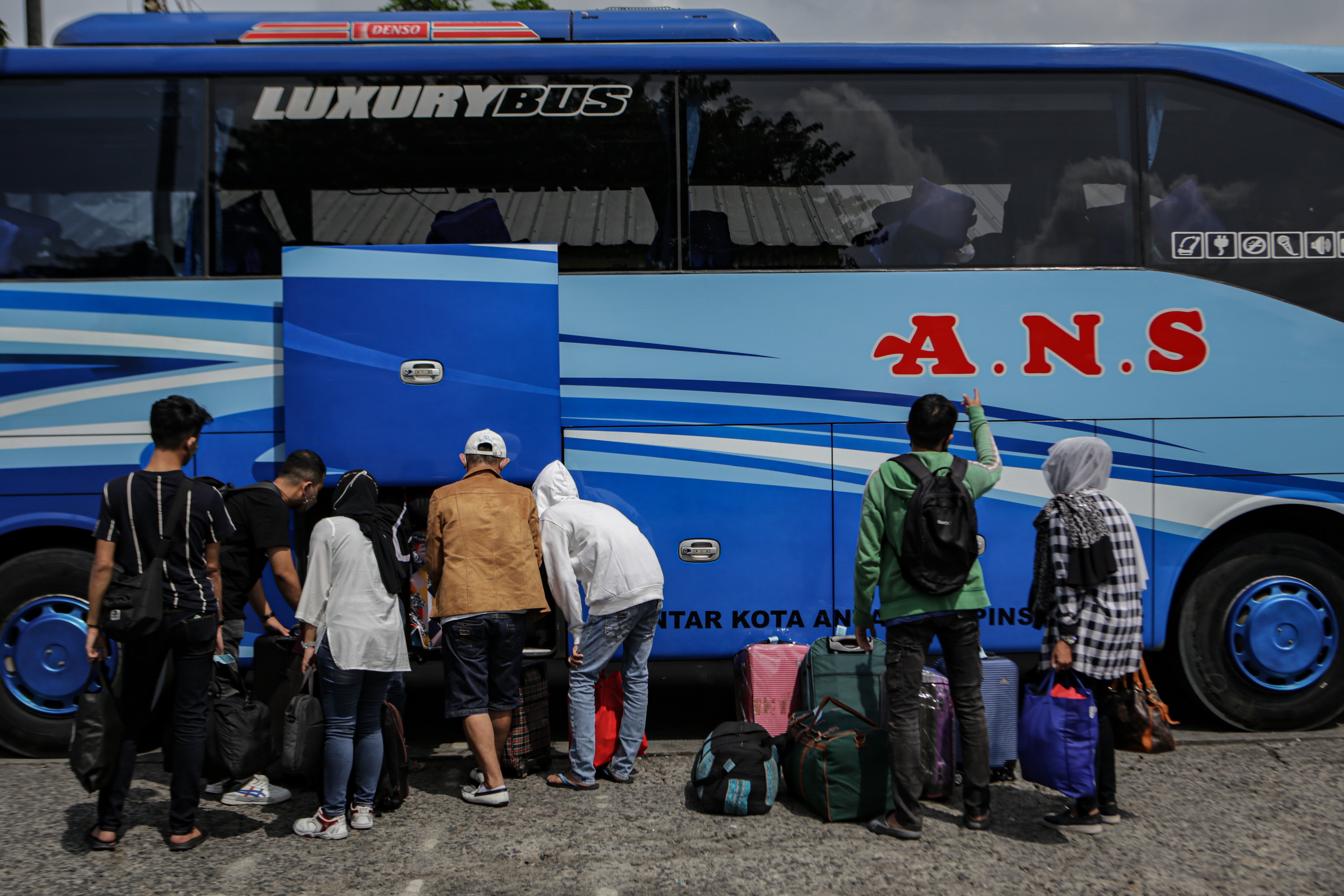 Calon pemudik memasukkan barang ke dalam bus yang hendak ditumpangi