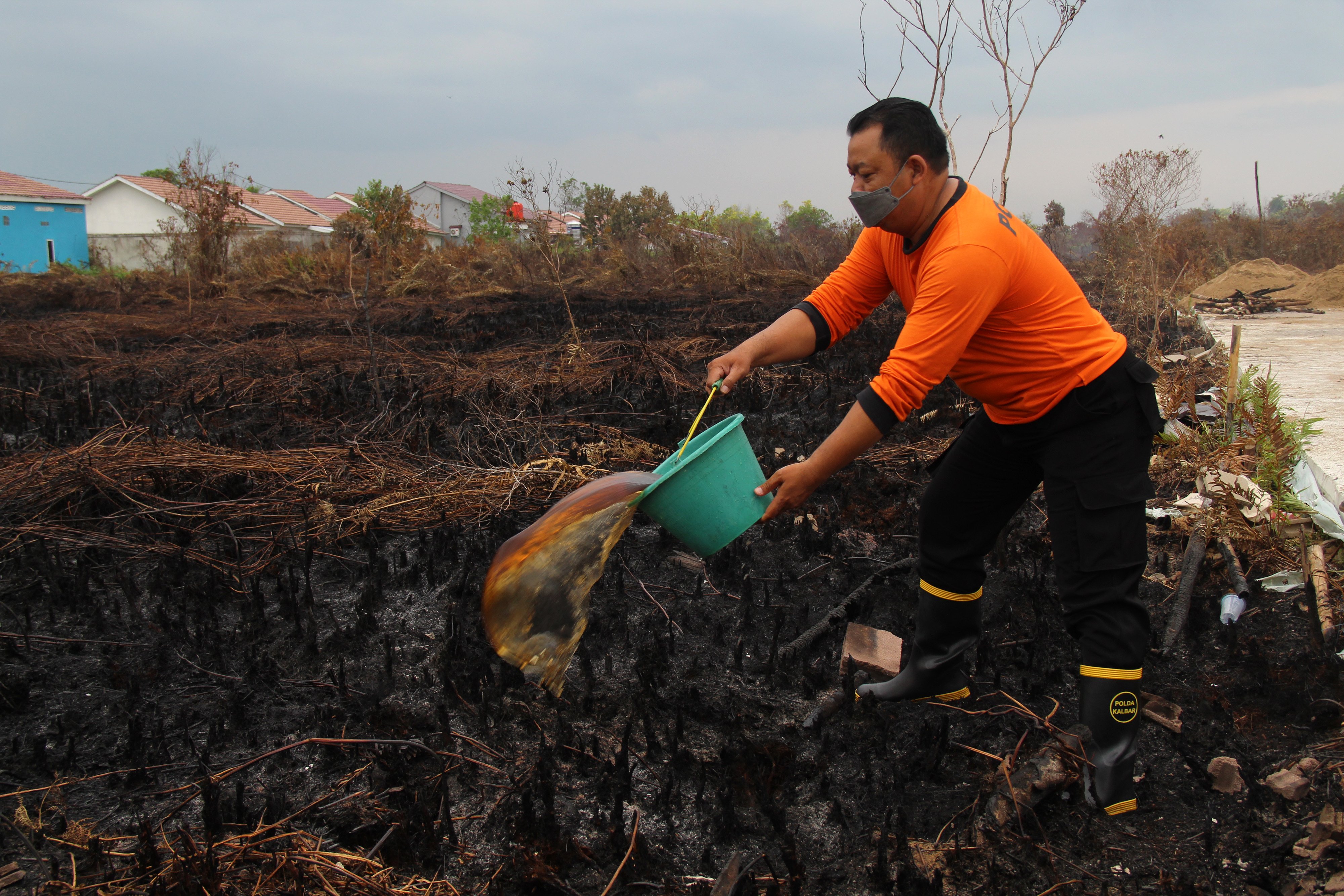 Seorang petugas menyiram air ke lahan gambut yang telah habis terbakar di Jalan Aloe Vera, Pontianak, Kalimantan Barat, Selasa (15/3/2022)