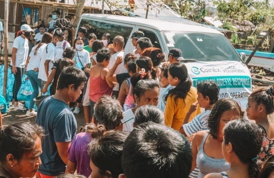 Petugas CoinEx Charity membagikan paket bantuan kepada warga yang kurang mampu.