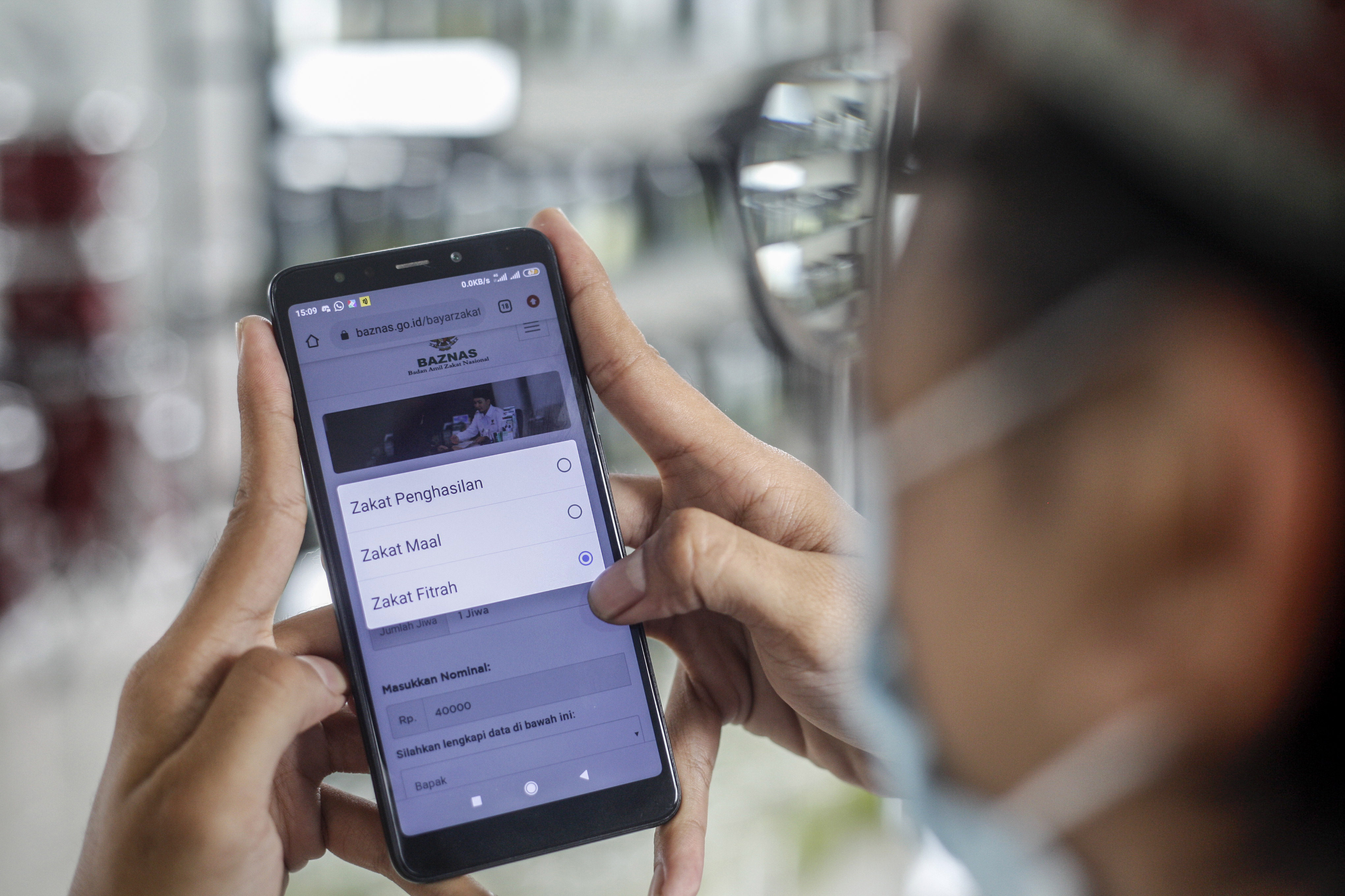 Warga membayarkan zakat fitrah dan zakat mal melalui laman resmi Badan Amil Zakat Nasional (Baznas) di perangkat telepon pintarnya