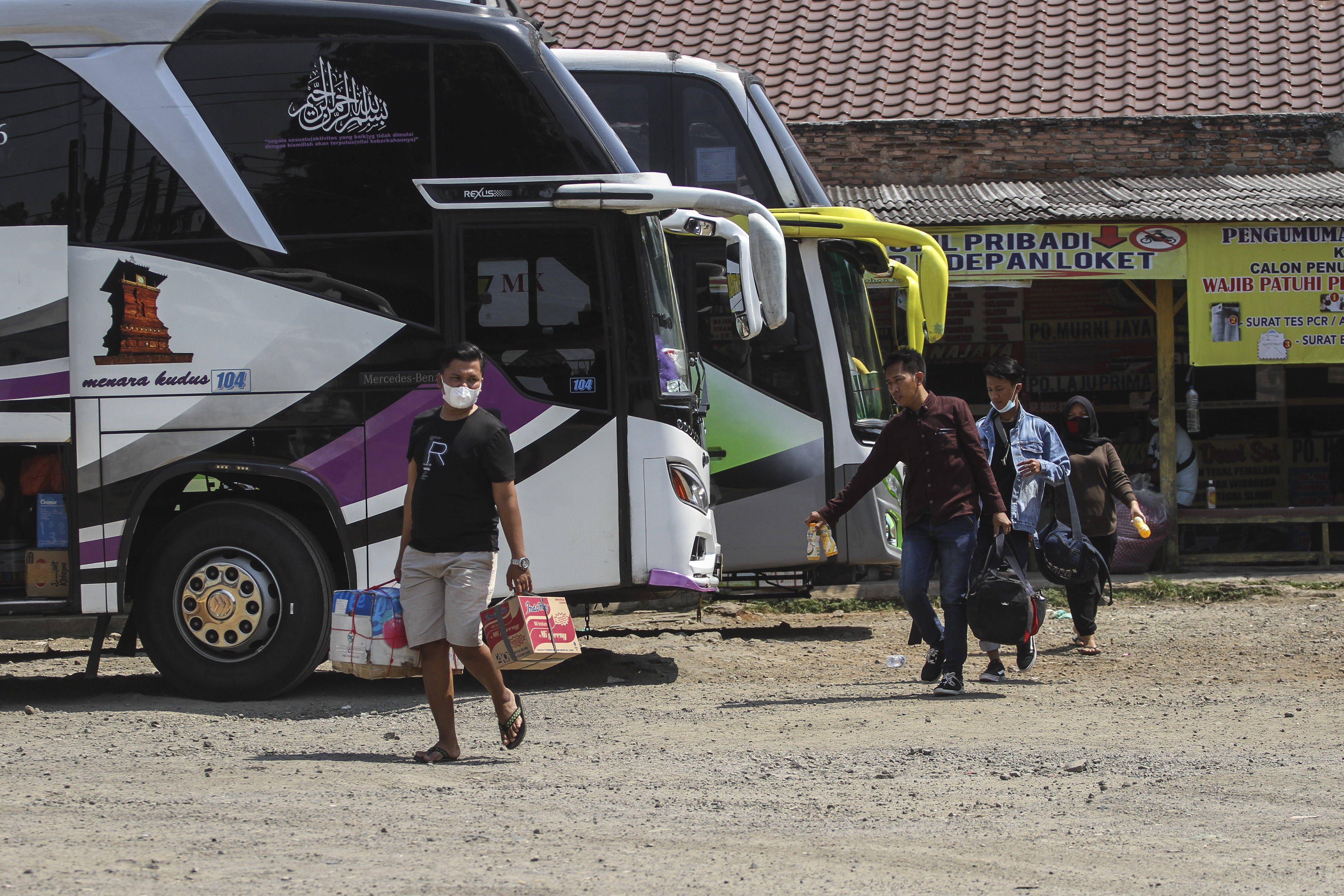 Calon penumpang melintas di area parkir bus AKAP di Terminal Bayangan Pondok Pinang, Jakarta.
