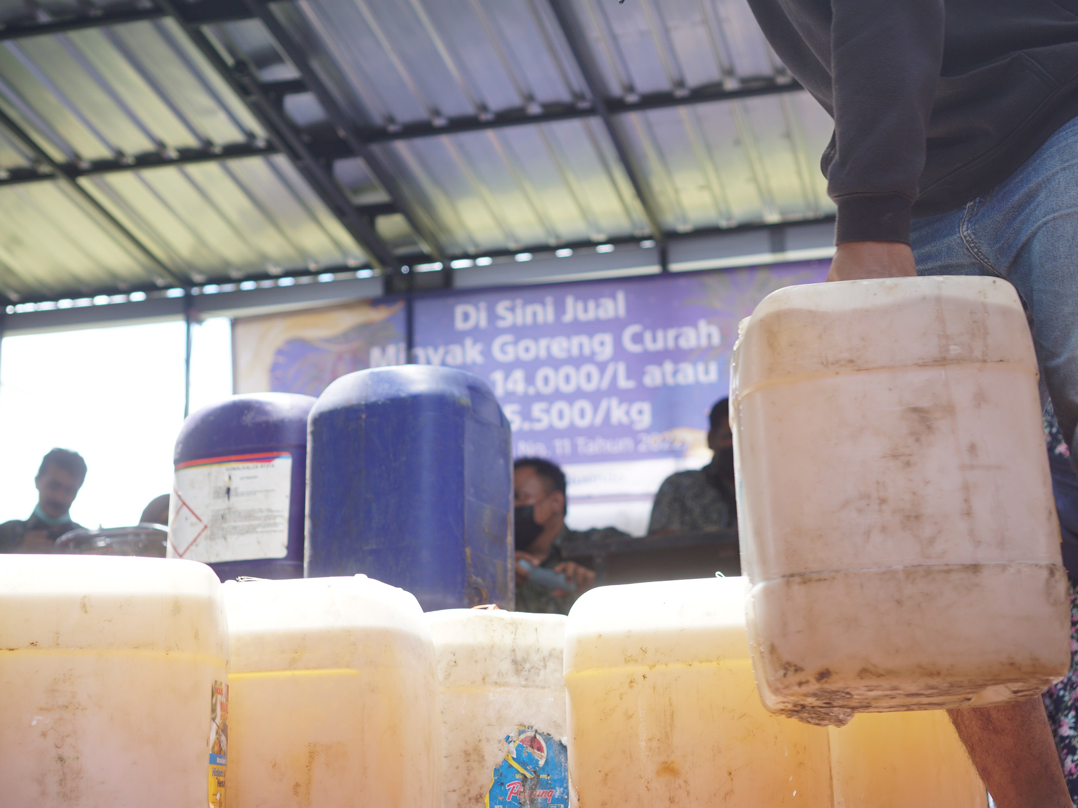 Warga menjinjing jeriken minyak goreng curah yang didapat dari operasi pasar minyak goreng murah di halaman kantor BPBD Tulungagung, Jatim.