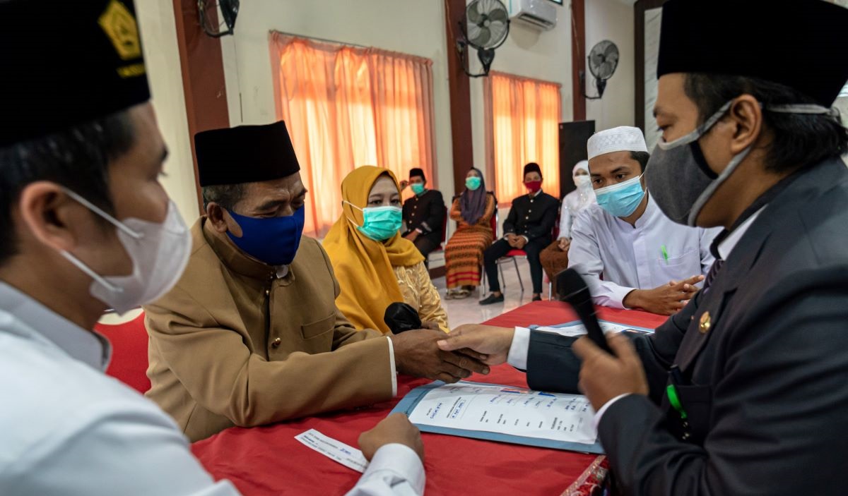 Pasangan pengantin mengikuti prosesi akad nikah dalam acara nikah massal di aula Kecamatan Genuk, Semarang, Jawa Tengah, Selasa (12/4).