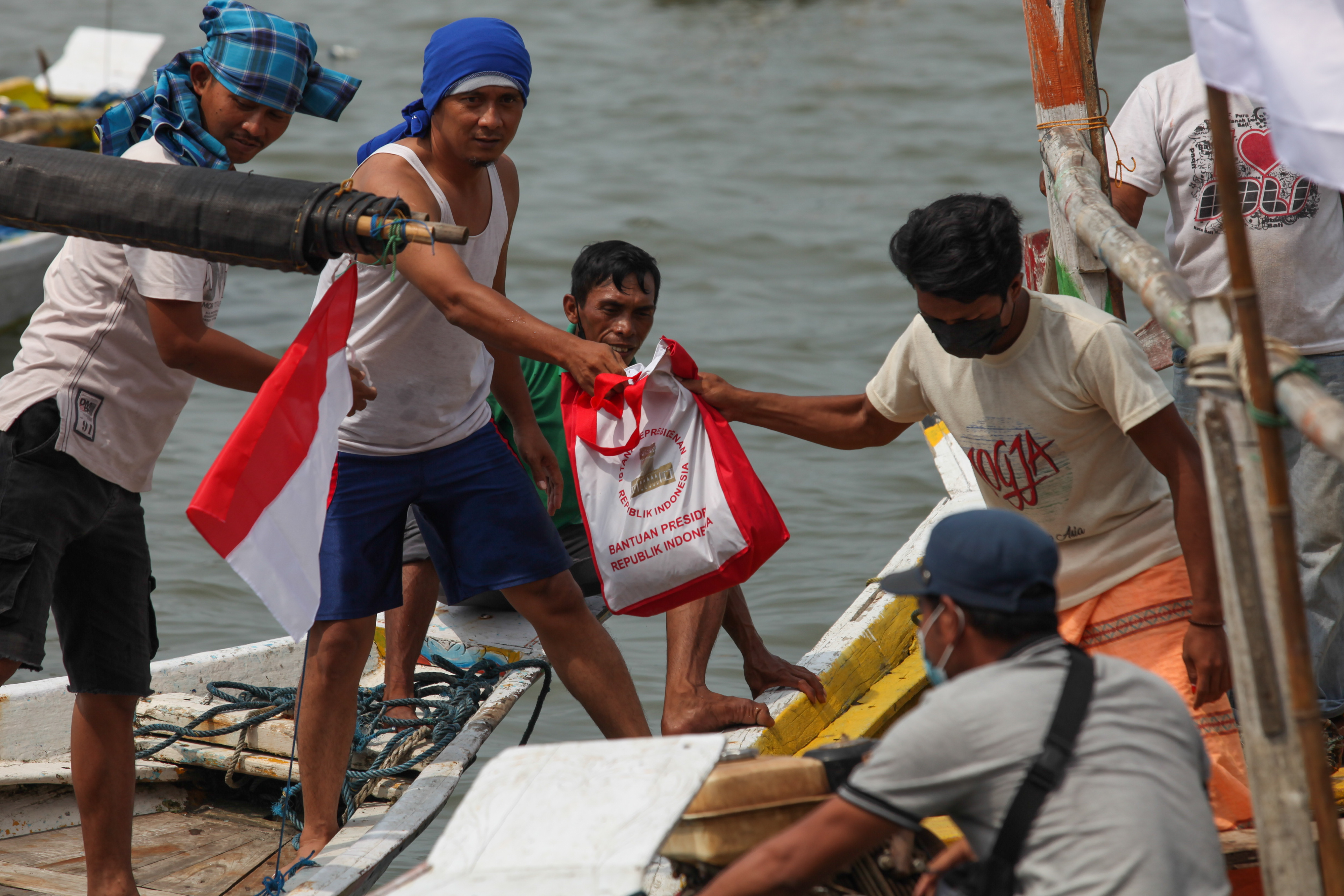 Sejumlah nelayan membawa paket bantuan yang diperoleh sebelum kedatangan Presiden Jokowi.