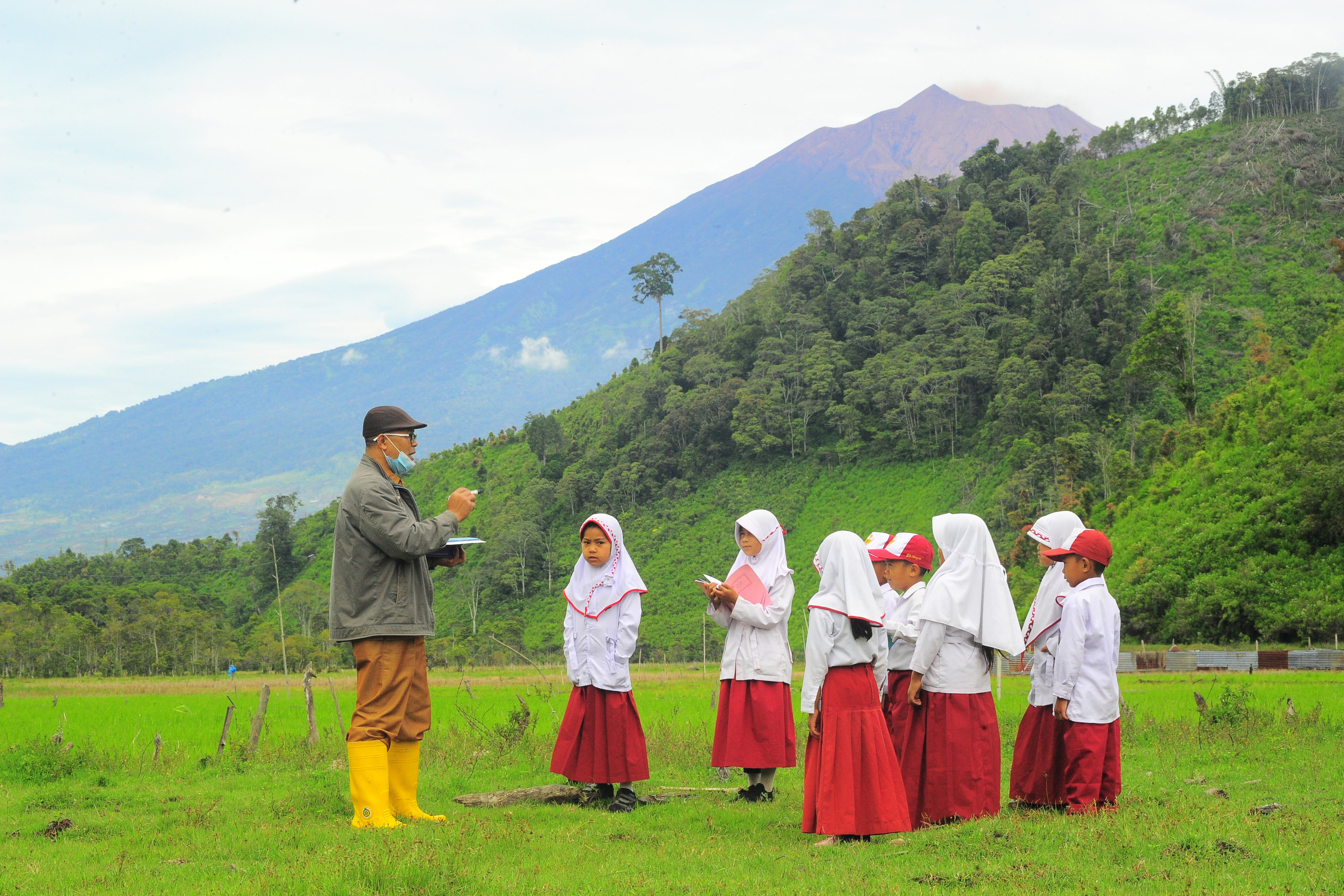 Seorang guru memberikan materi luar kelas kepada beberapa muridnya di SDN 226/III Renah Kasah, Kerinci, Jambi, Senin (4/1/2021)