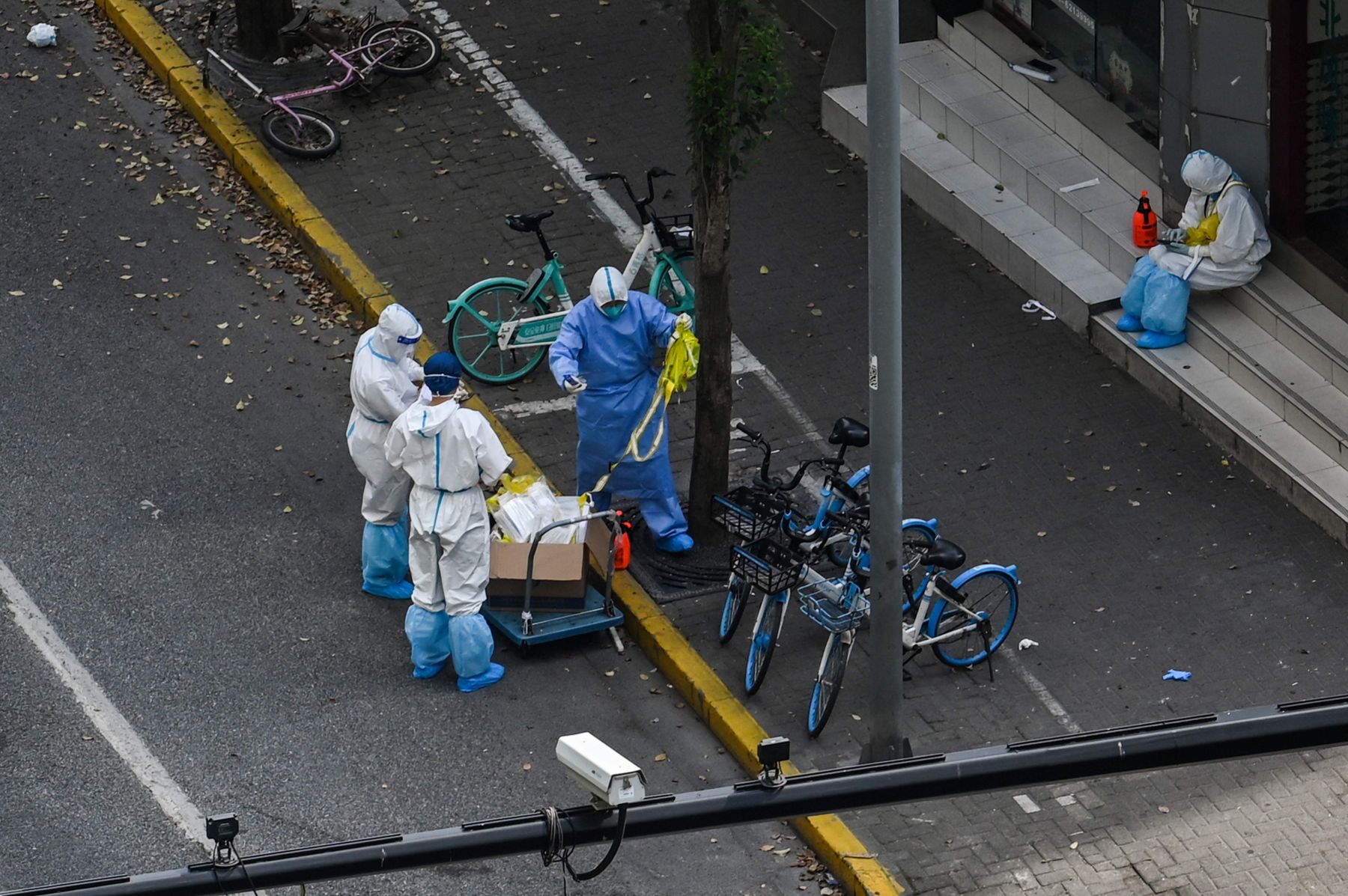 Petugas dengan menggunakan alat pelindung diri bersiaga di gerbang masuk permukiman di Distrik Jing'an, Shanghai, Tiongkok, Selasa (12/4). 
