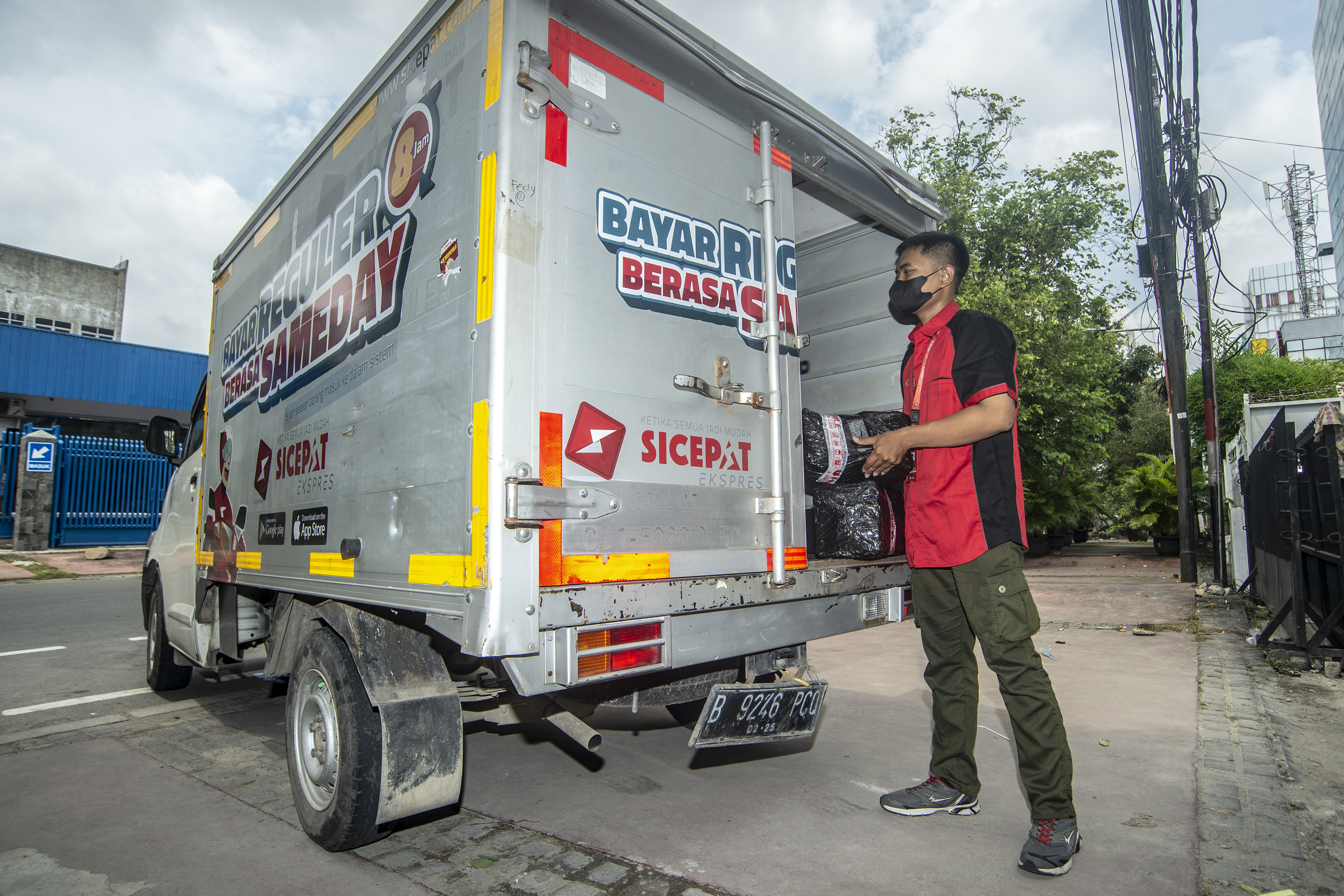 Petugas jasa ekspedisi SiCepat Ekspres memasukan barang ke dalam mobil untuk dilakukan pengiriman di Gerai Kebon Kelapa, Jakarta.