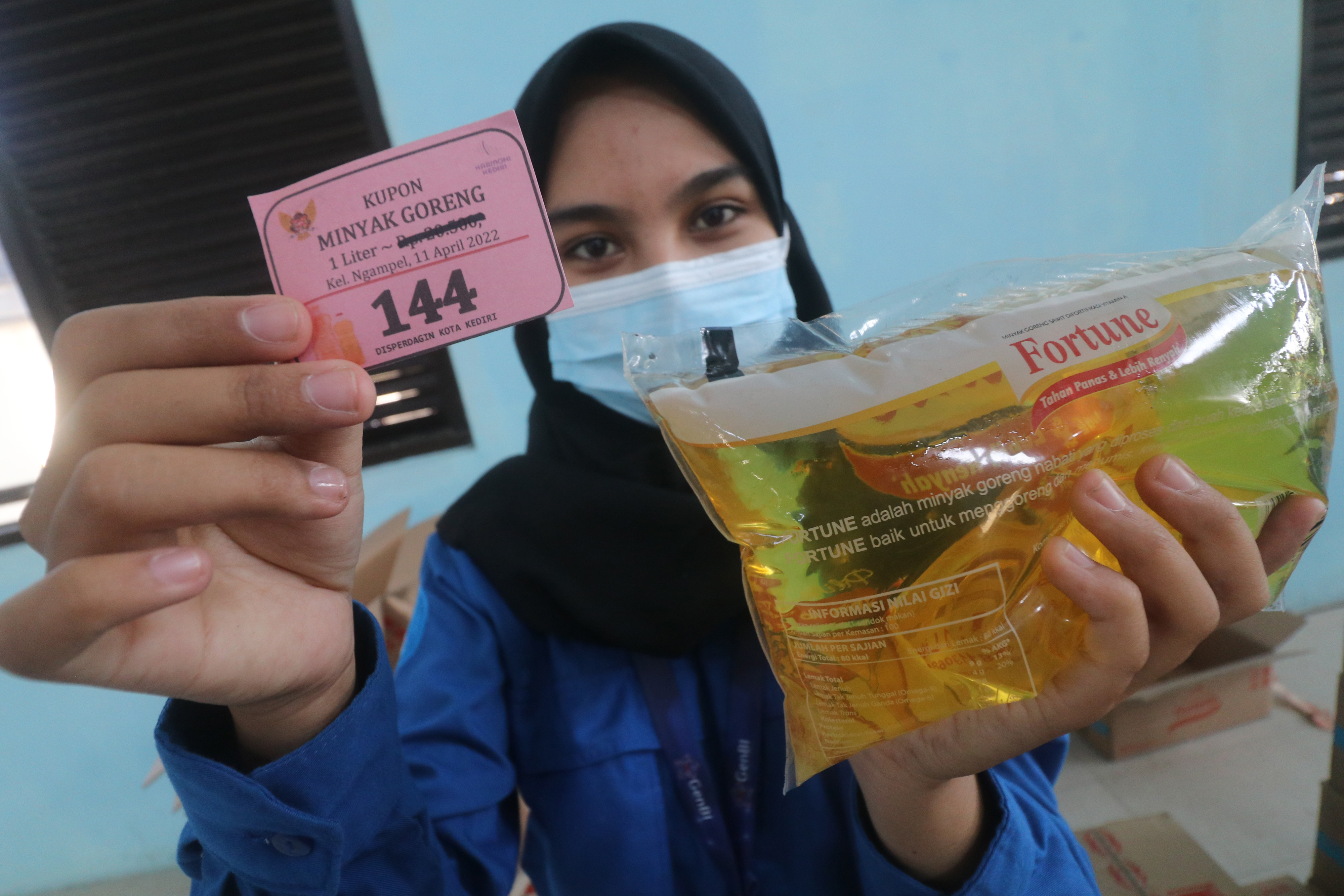 Warga memperlihatkan kupon pembelian minyak goreng berharga murah saat operasi pasar murni di Kelurahan Ngampel, Kota Kediri, Jawa Timur.