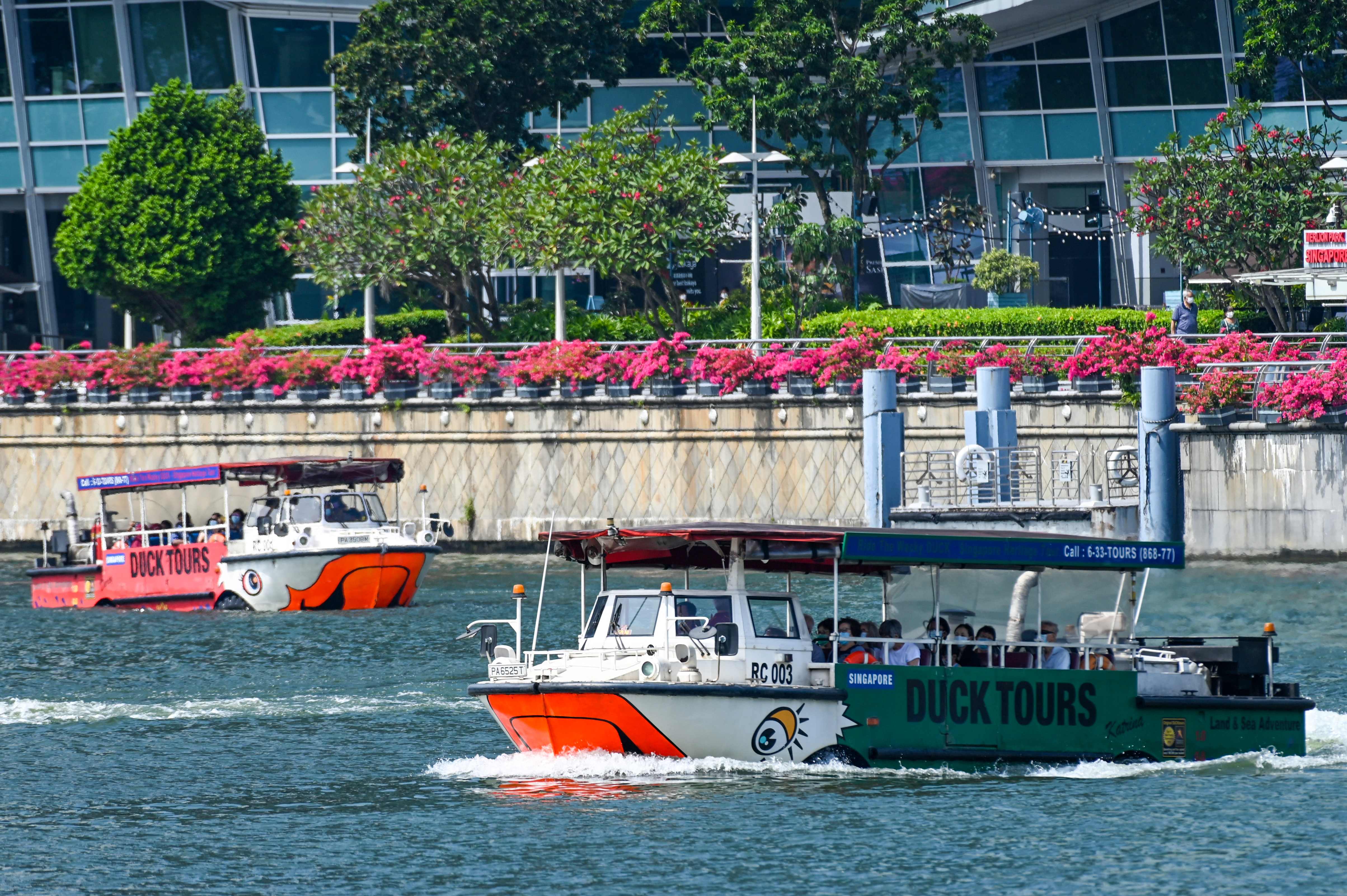 Para turis lokal dan mancanegara menaiki boat yang berlayar di sekitar waterfront Marina Bay, Singapura.