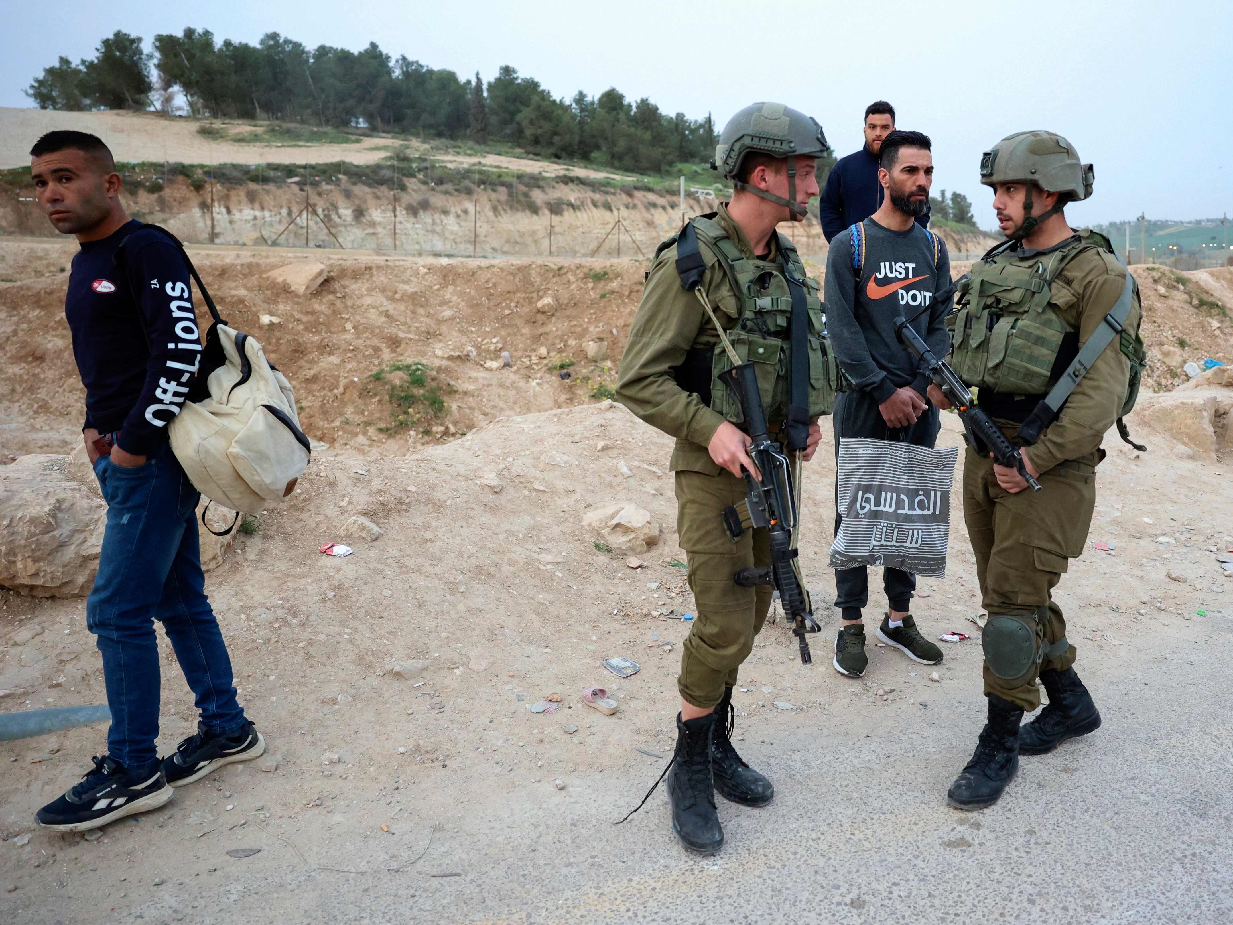 Pria Palestina menyaksikan pasukan keamanan Israel menutup dan mengontrol pelanggaran di pagar penghalang dekat pos pemeriksaan Mitar.