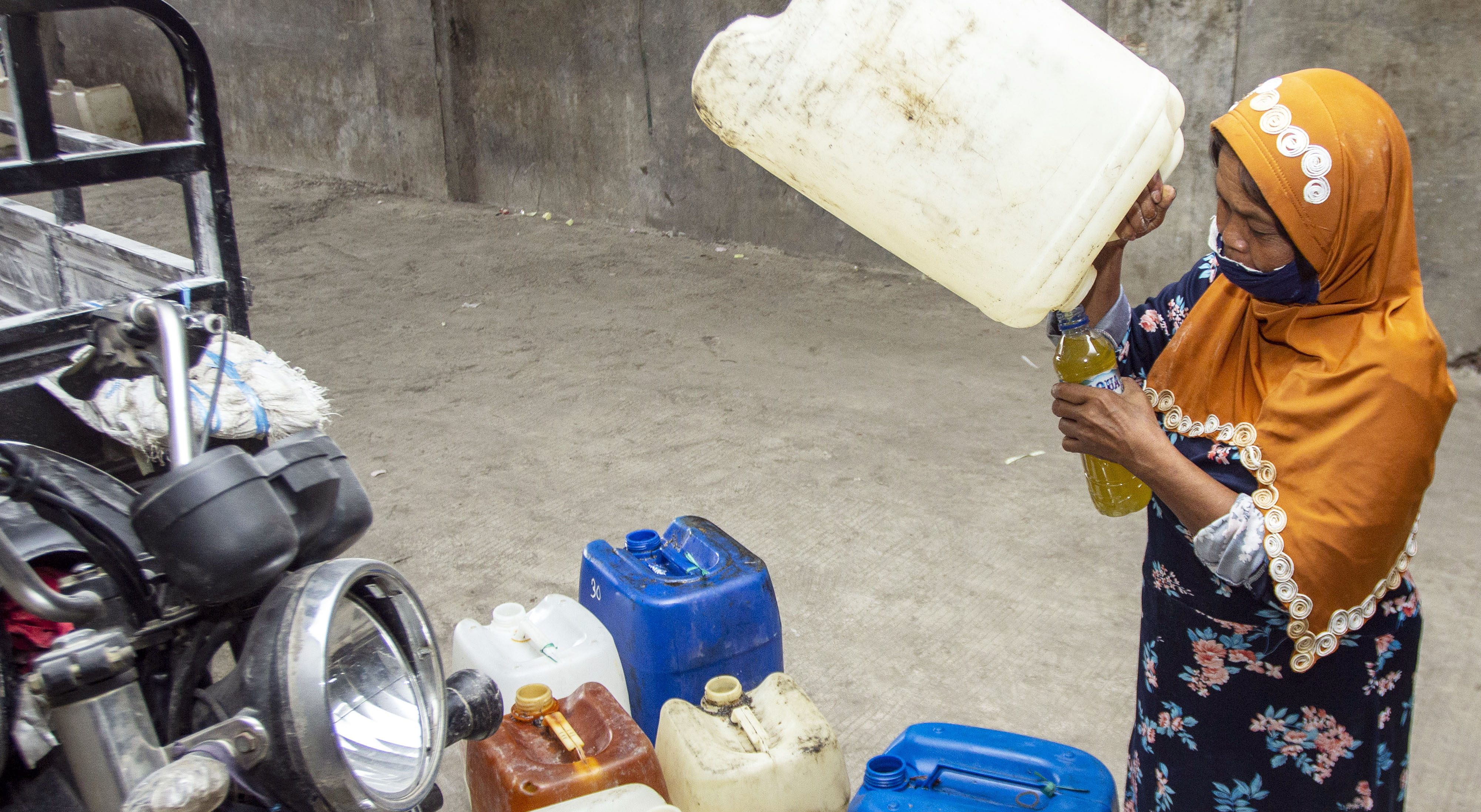 Warga mengambil sisa minyak goreng dari jeriken yang akan diisi minyak goreng curah.