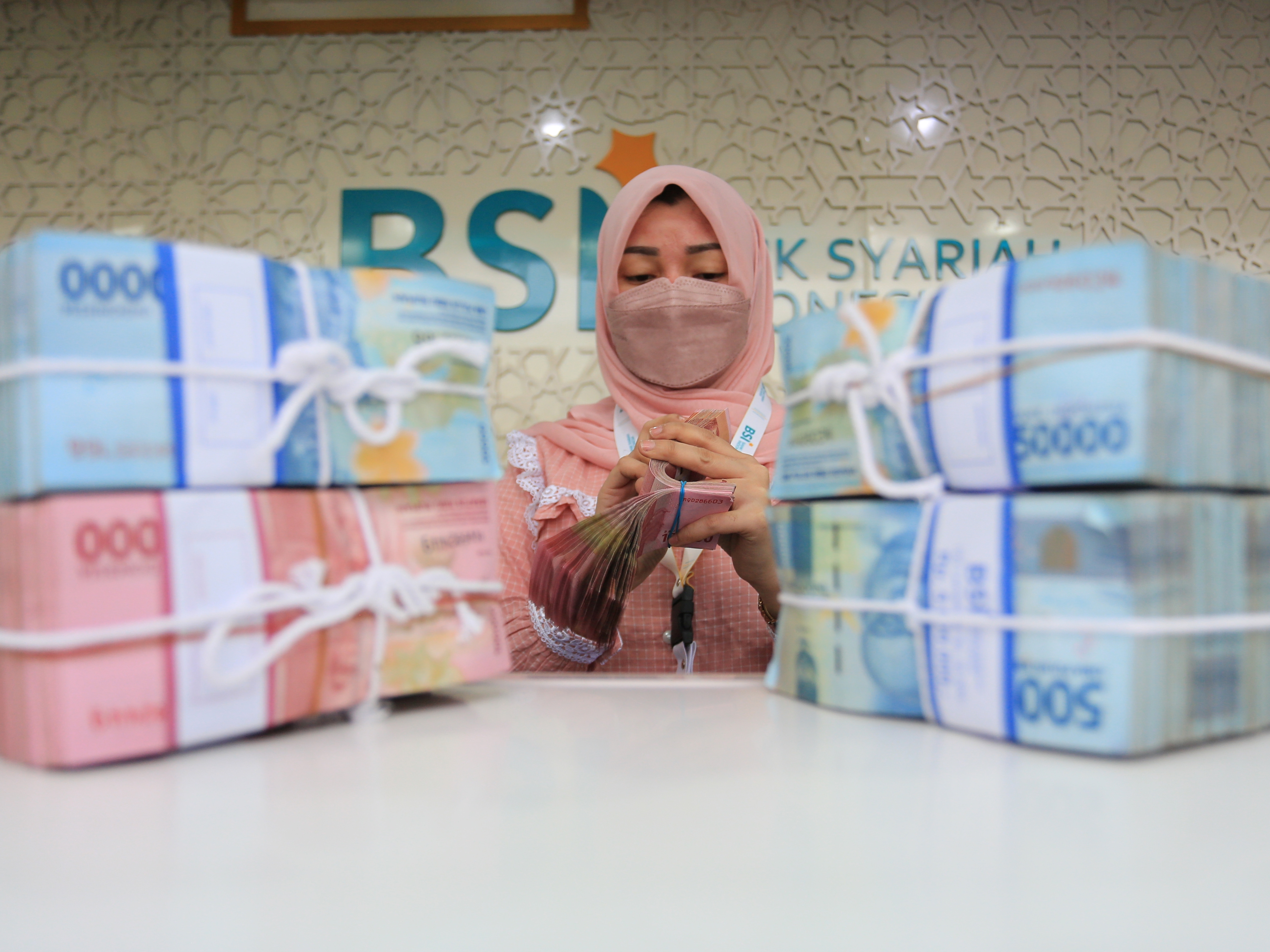Karyawati BSI menghitung uang rupiah di Kantor Cabang Pembantu (KCP) Daud Beureueh, Banda Aceh, Aceh, Jumat (21/1).
