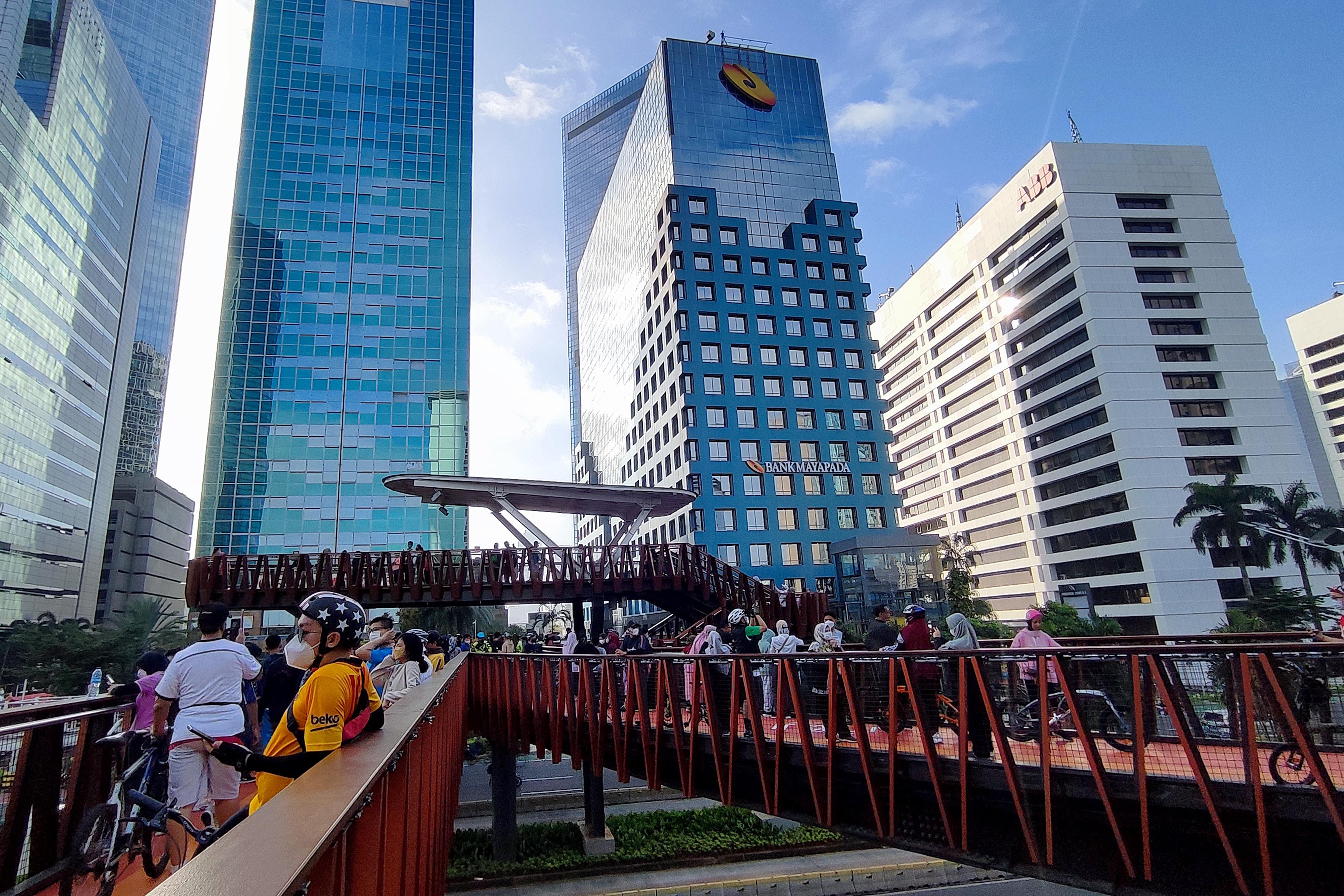 Warga berada di JPO Pinisi, akarta dengan latar belakang gedung bertingkat