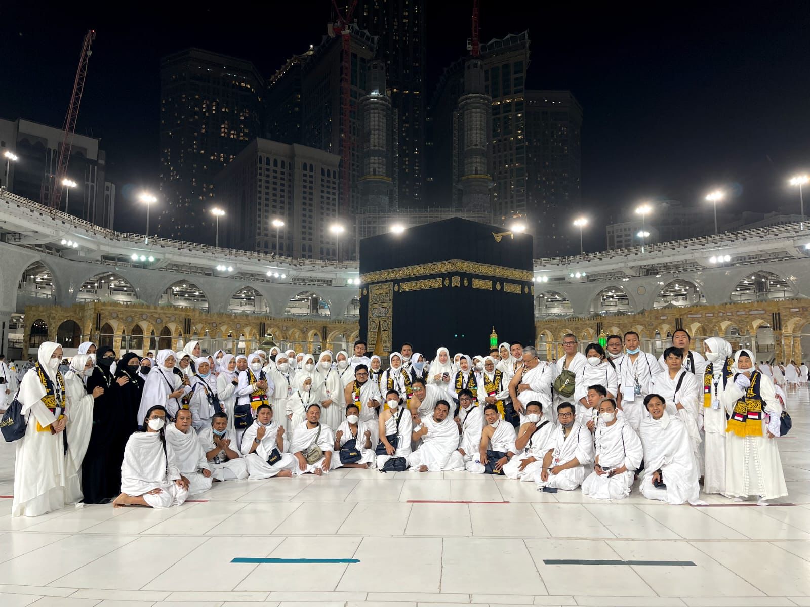 Para jemaah umrah berpose dengan latar belakang Kabah dan Masjid Al-Haram. 