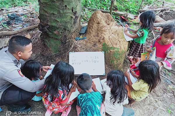 Bripda Seri Santoso, satu  bintara muda Polda Jambi tengah asyik mengajari anak-anak SAD (Suku Anak Dalam) pelajaran calistung