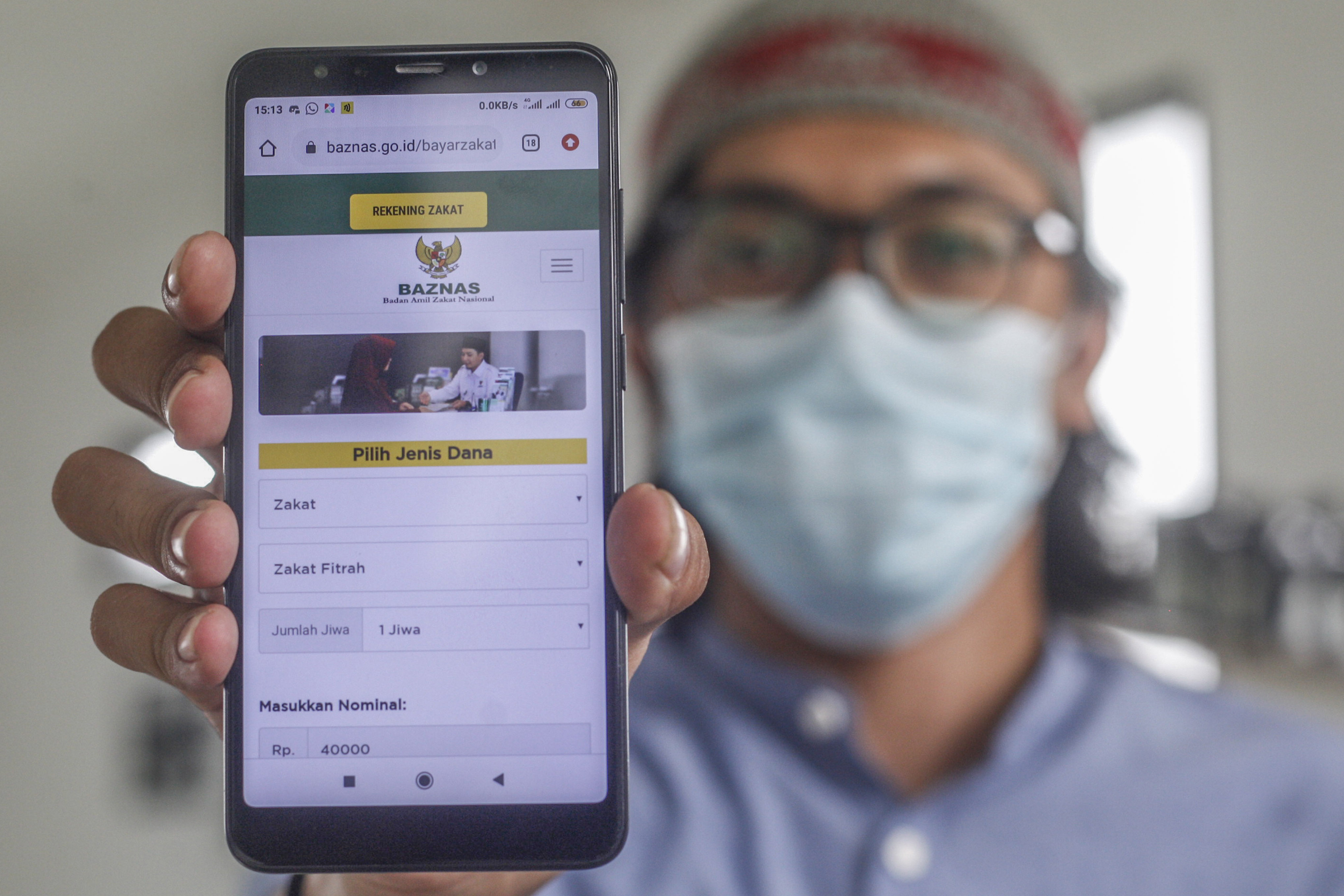 Warga menunjukan laman resmi Baznas melalui perangkat telepon pintar.