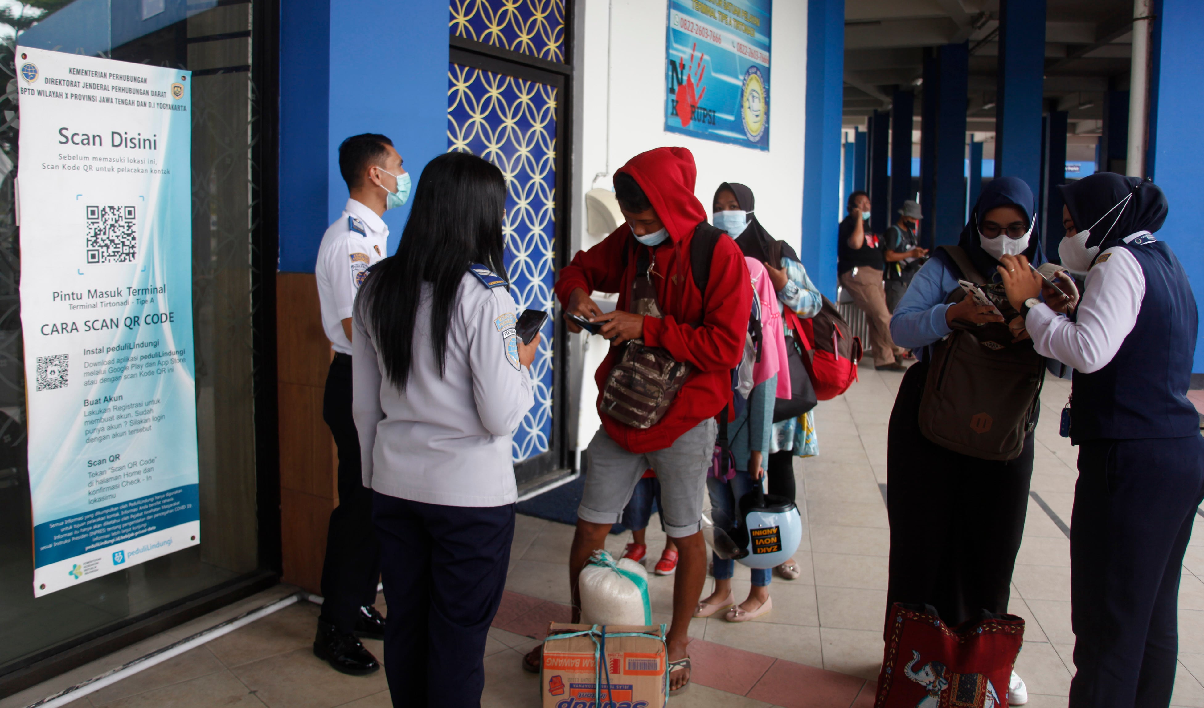  Petugas memeriksa sertifikat vaksin covid-19 dan membagikan masker bagi penumpang yang tiba di Terminal Tirtonadi Solo, Jawa Tengah.