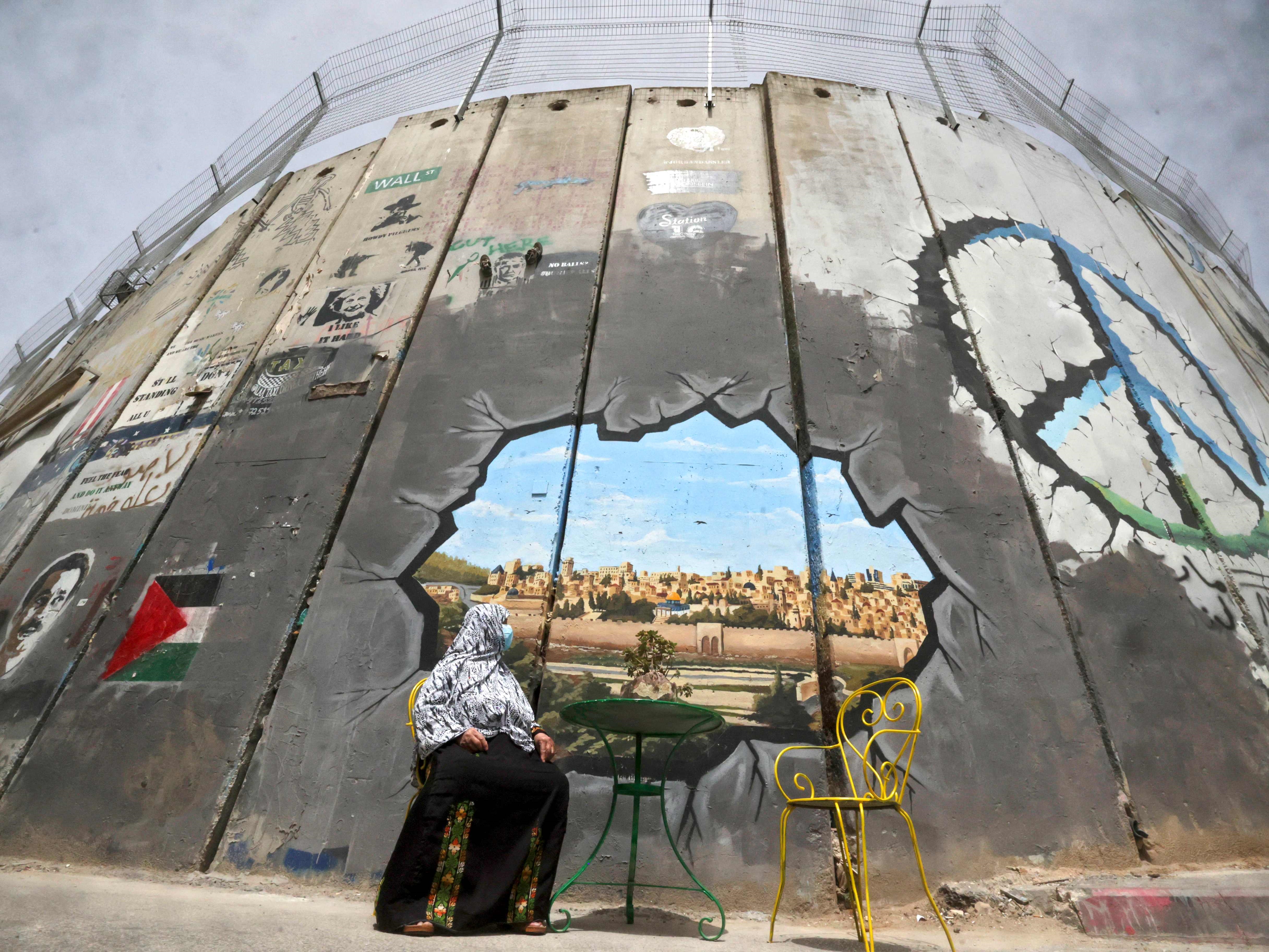 Wanita Palestina melihat mural yang menggambarkan kompleks masjid al-Aqsa dan kota tua Jerusalem tentang batas pemisah buatan Israel.