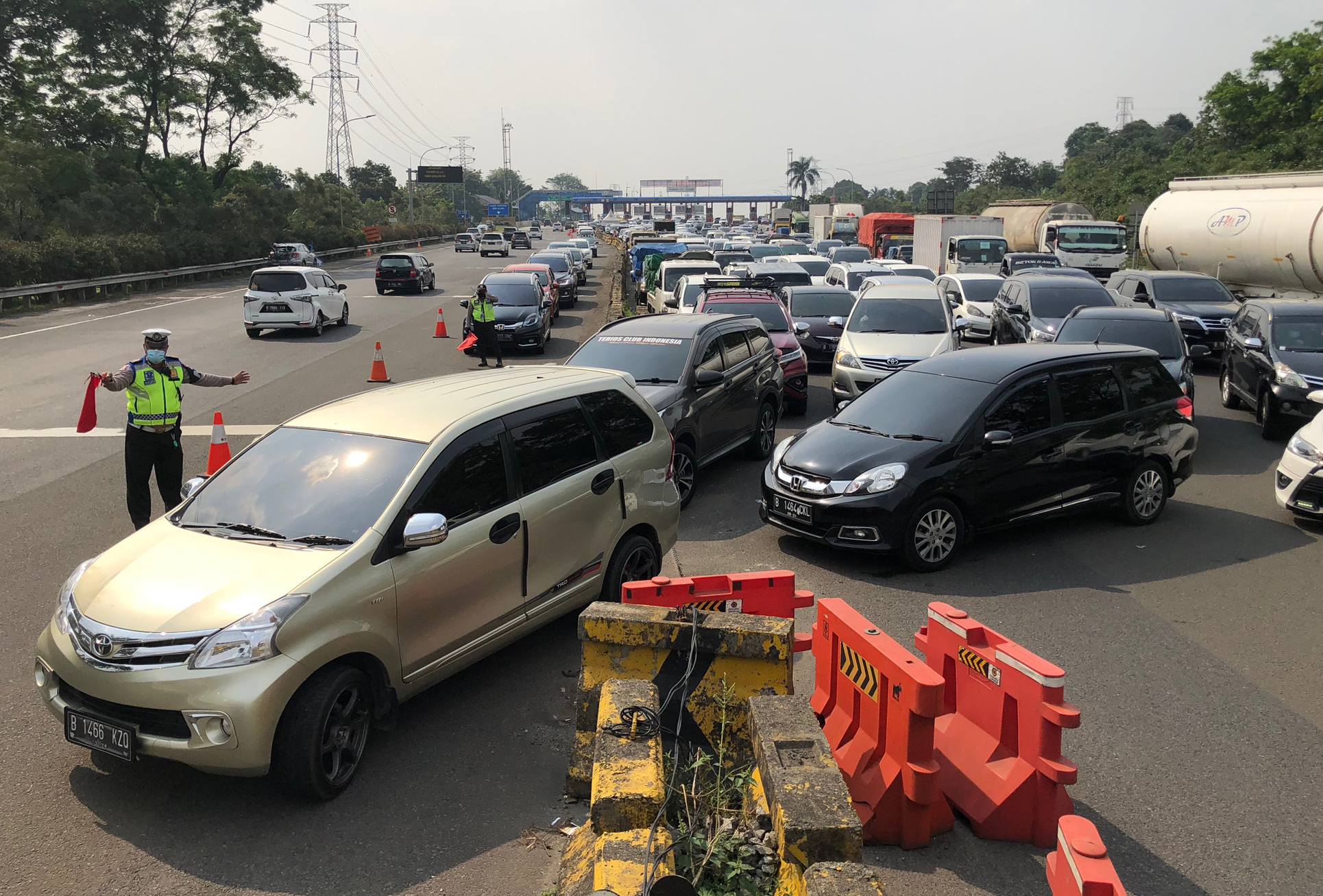 Petugas mengatur kendaraan di pintu keluar Tol Jagorawi, Ciawi, pada penerapan kebijakan ganjil genap