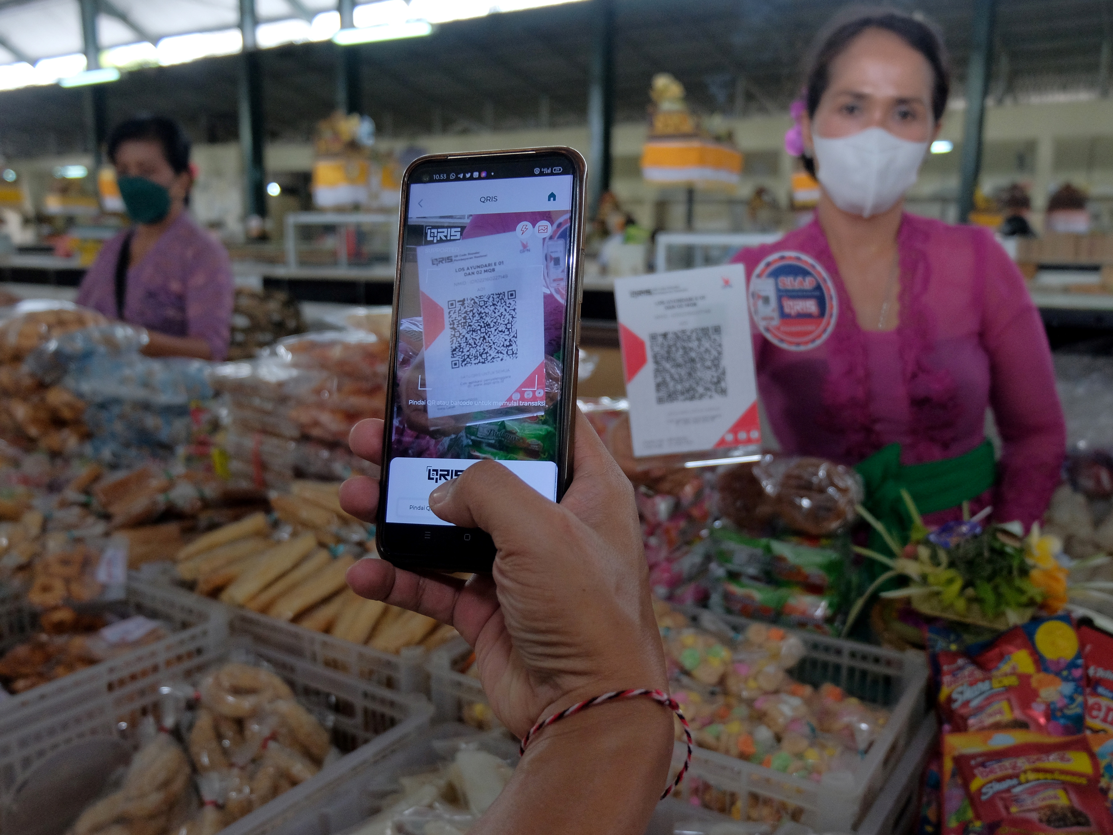 Warga melakukan pembayaran menggunakan fitur pemindai QRIS di Pasar Nyanggelan, Desa Panjer, Denpasar, Bali, Jumat (1/4/2022).