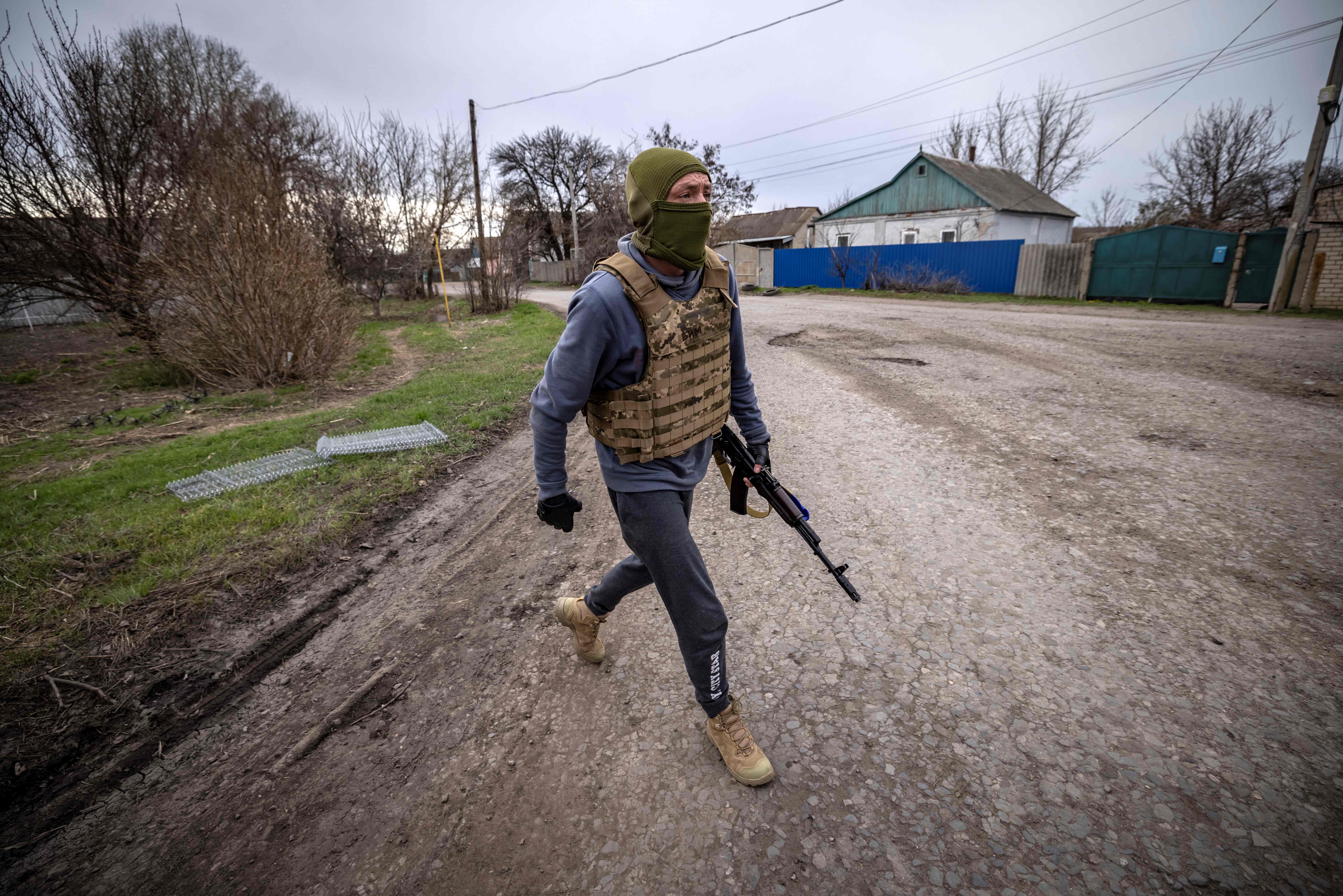 Pasukan penjaga teritori berjalan dengan menenteng senjata di Kota Barvinkove, wilayah timur Ukraina, Sabtu (9/4/2022).  